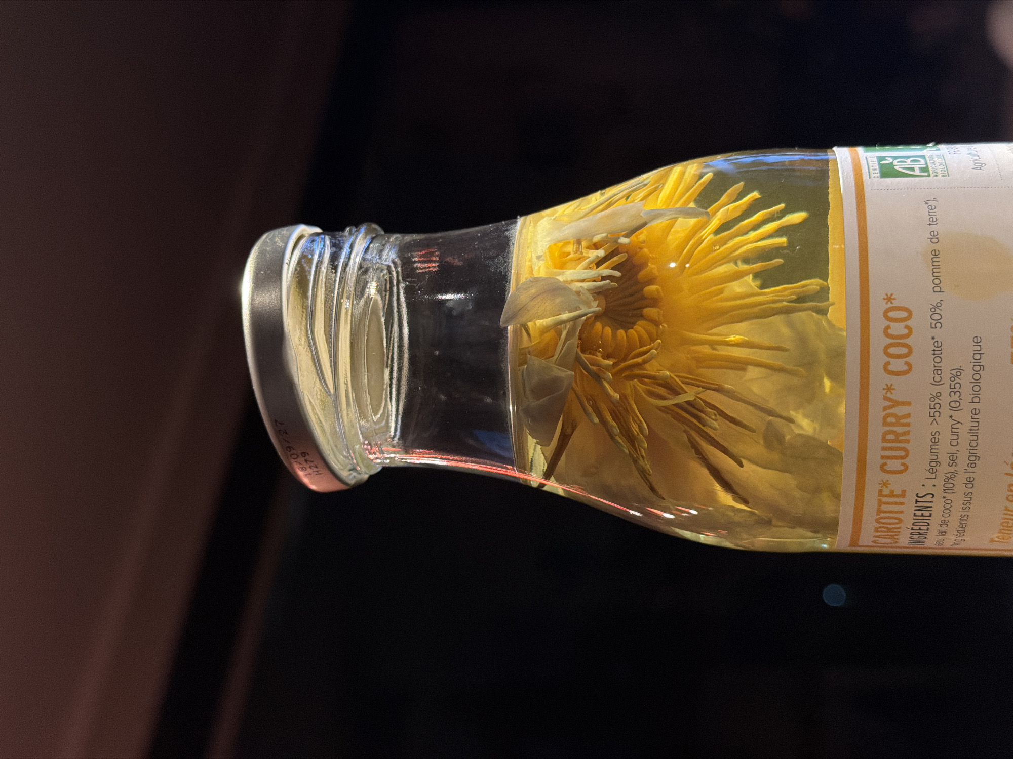 Flower preserved in yellow liquid inside a labeled glass bottle