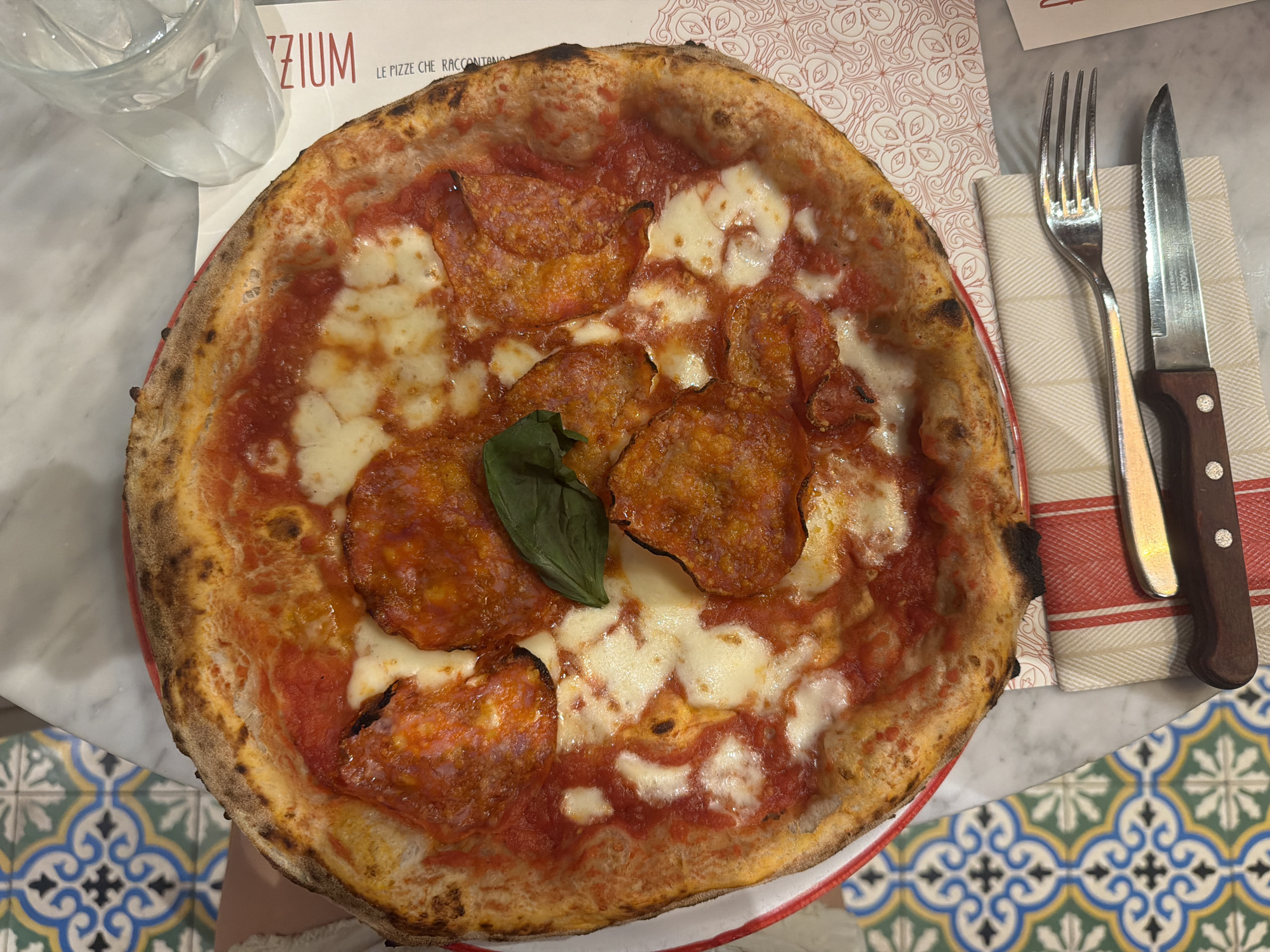 Overhead close-up of a charred-crust pepperoni pizza in Milan