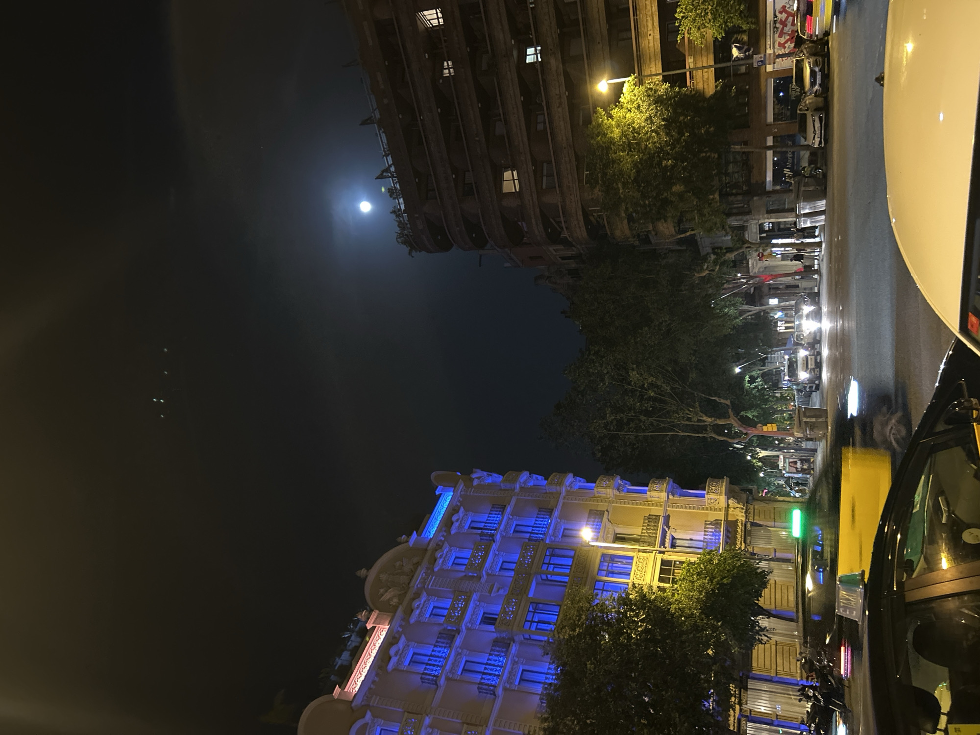 Full moon illuminates Barcelona street scene with parked taxis