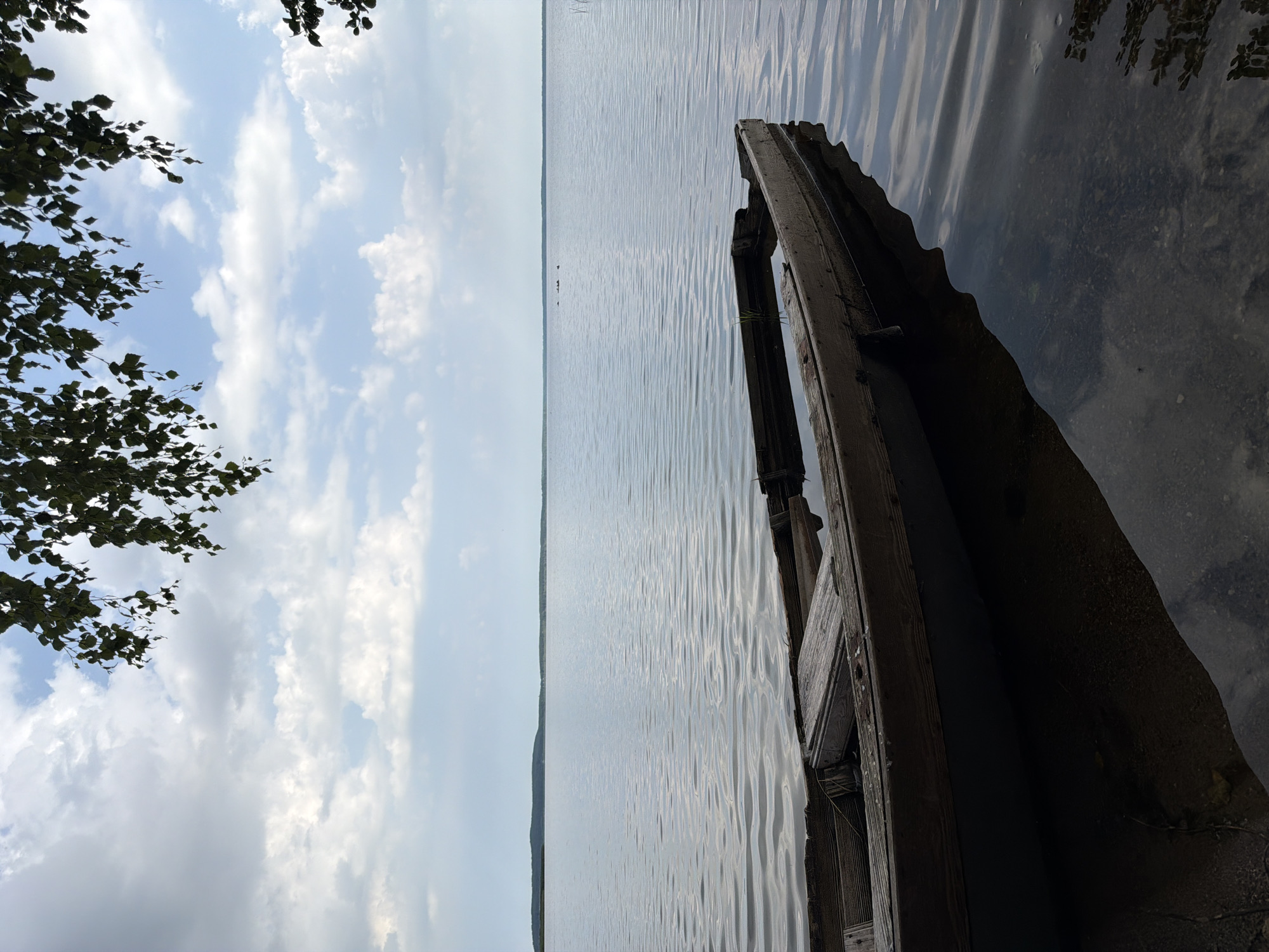 Weathered rowboat quietly sinking at a calm lakeshore