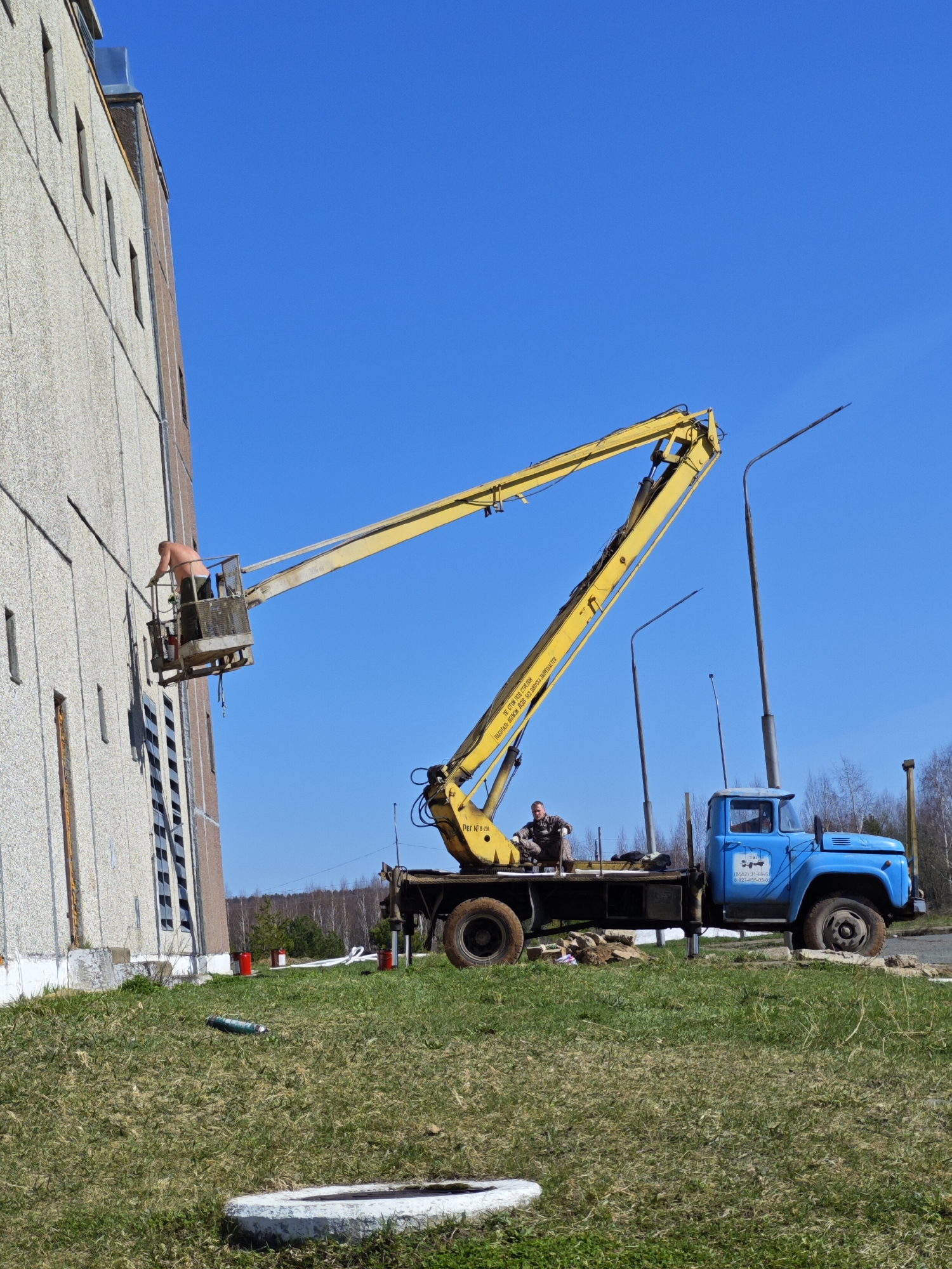 Workers operate aerial lift during maintenance in Markovskii, Russia