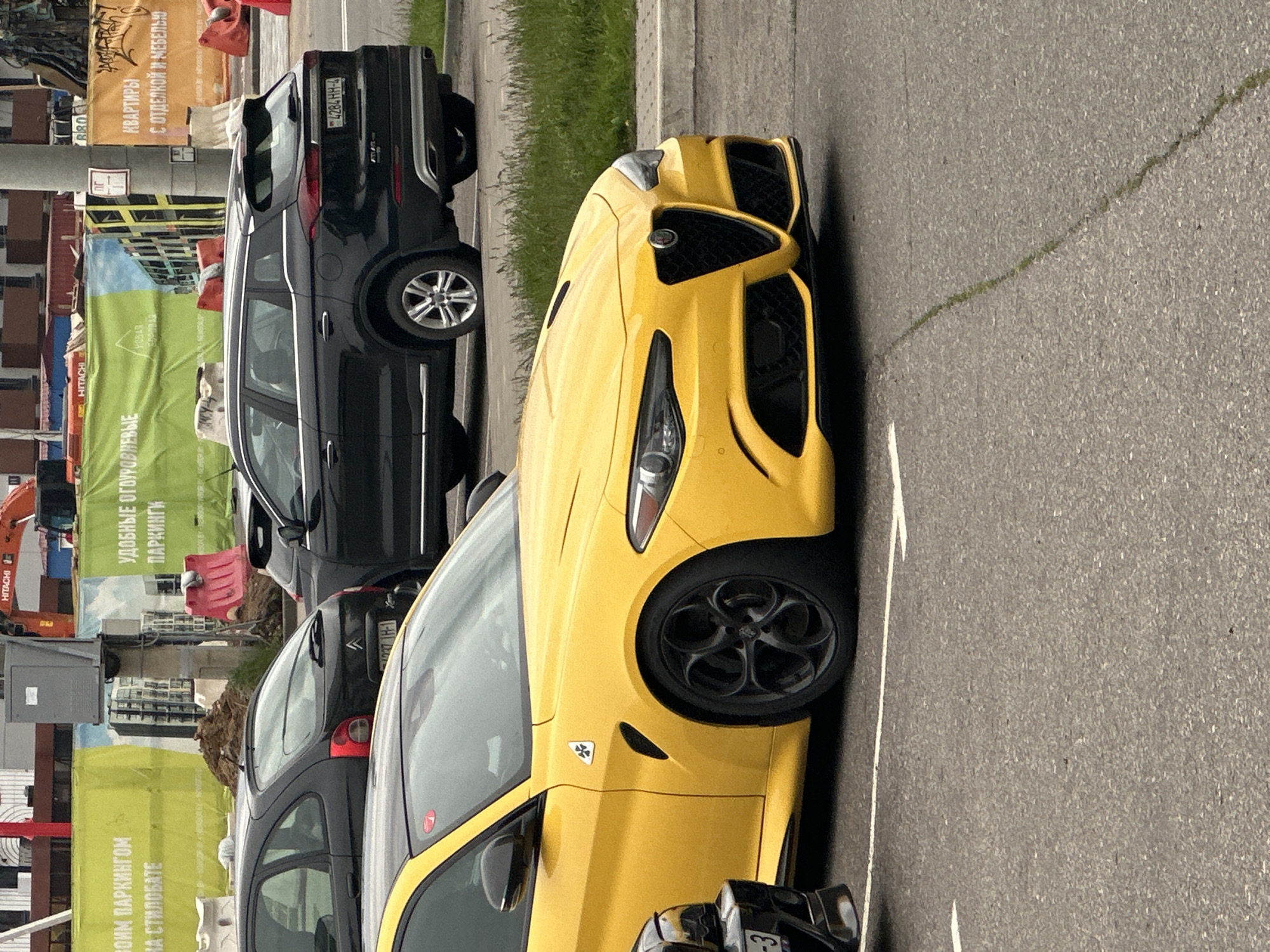 Vehicles including yellow Alfa Romeo parked in Belarus village