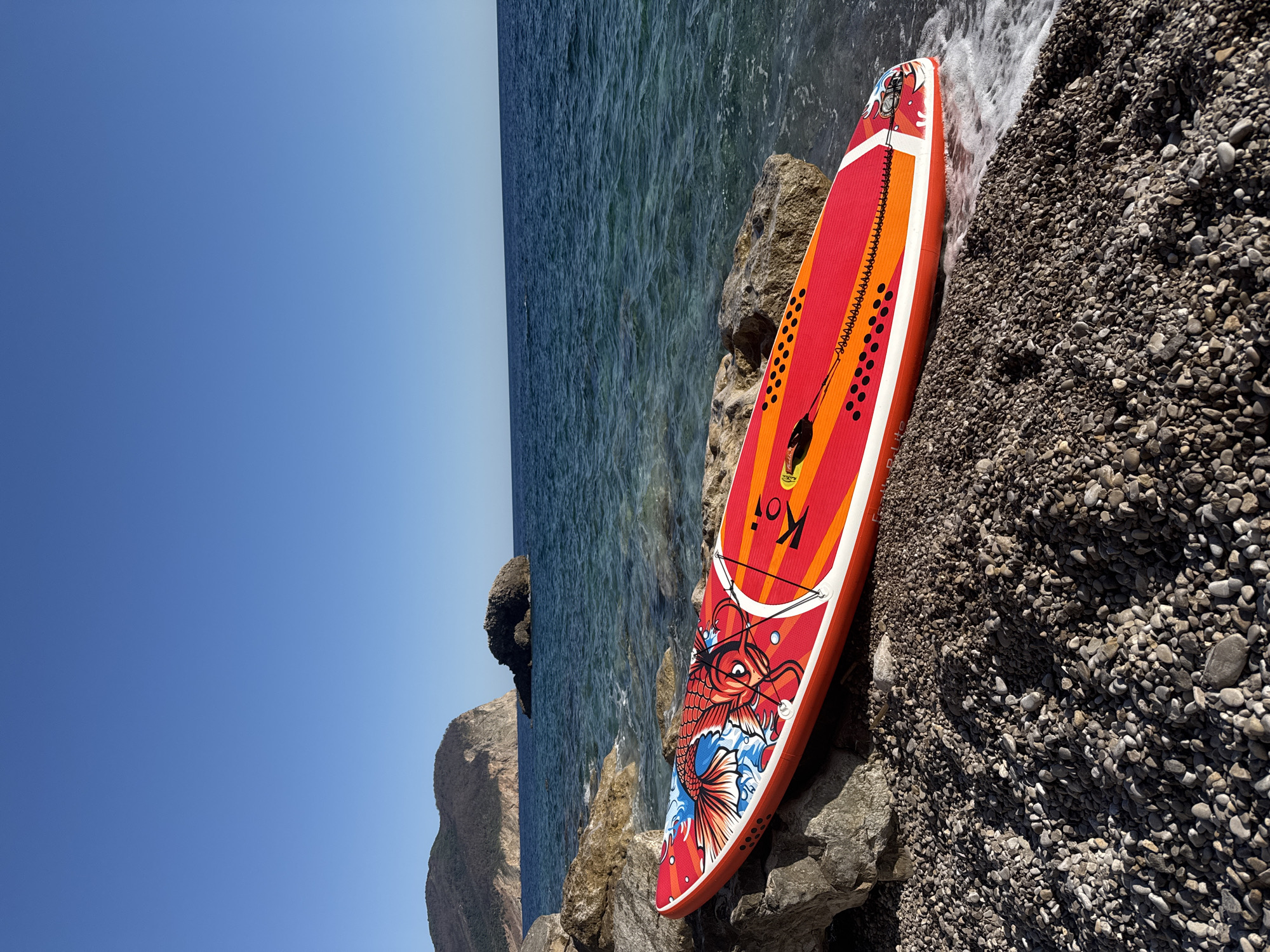 Koi-design paddleboard parked on a rocky Montenegrin beach