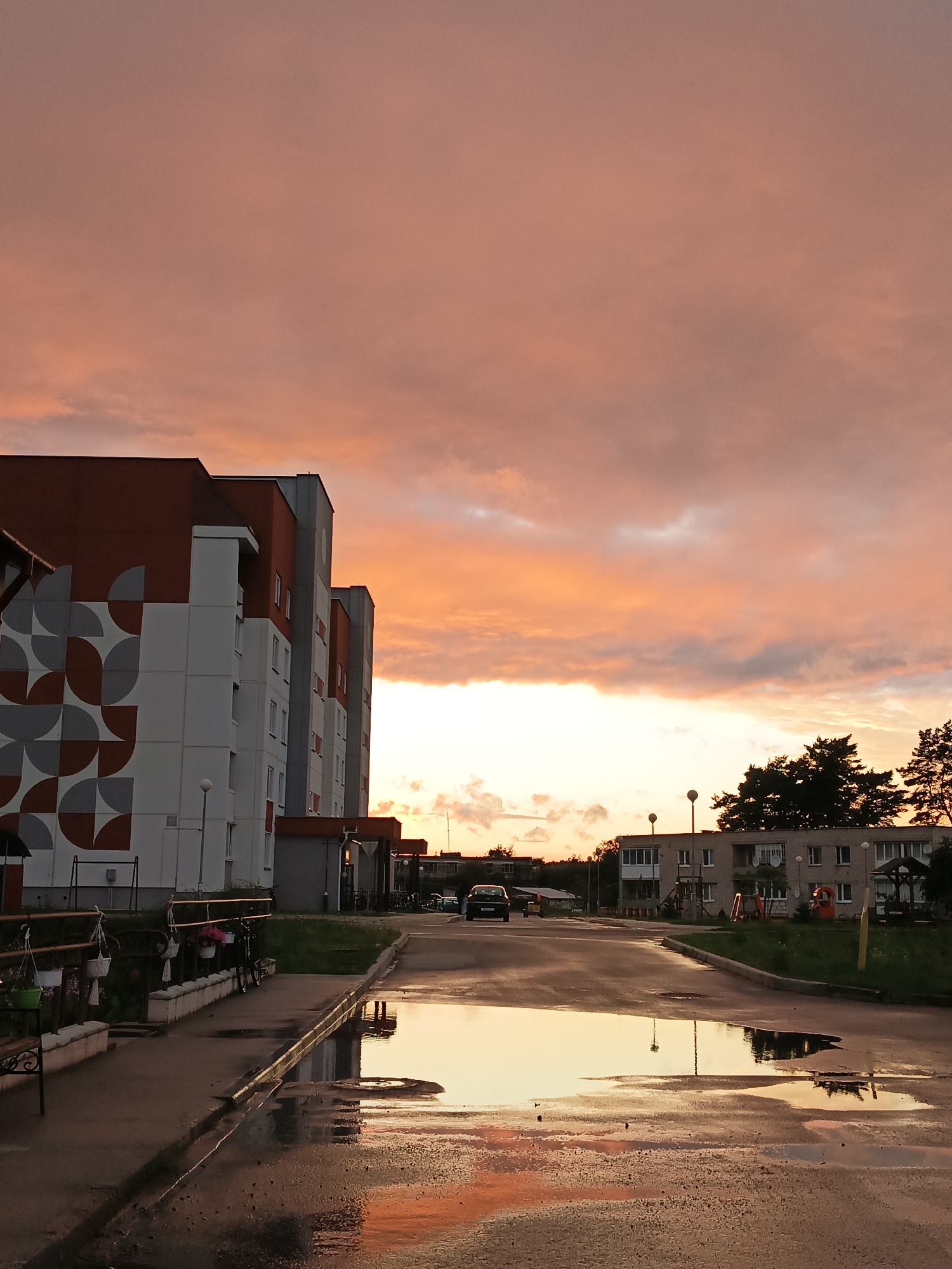 Post-rain puddles mirror a vivid sunset in rural Belarus