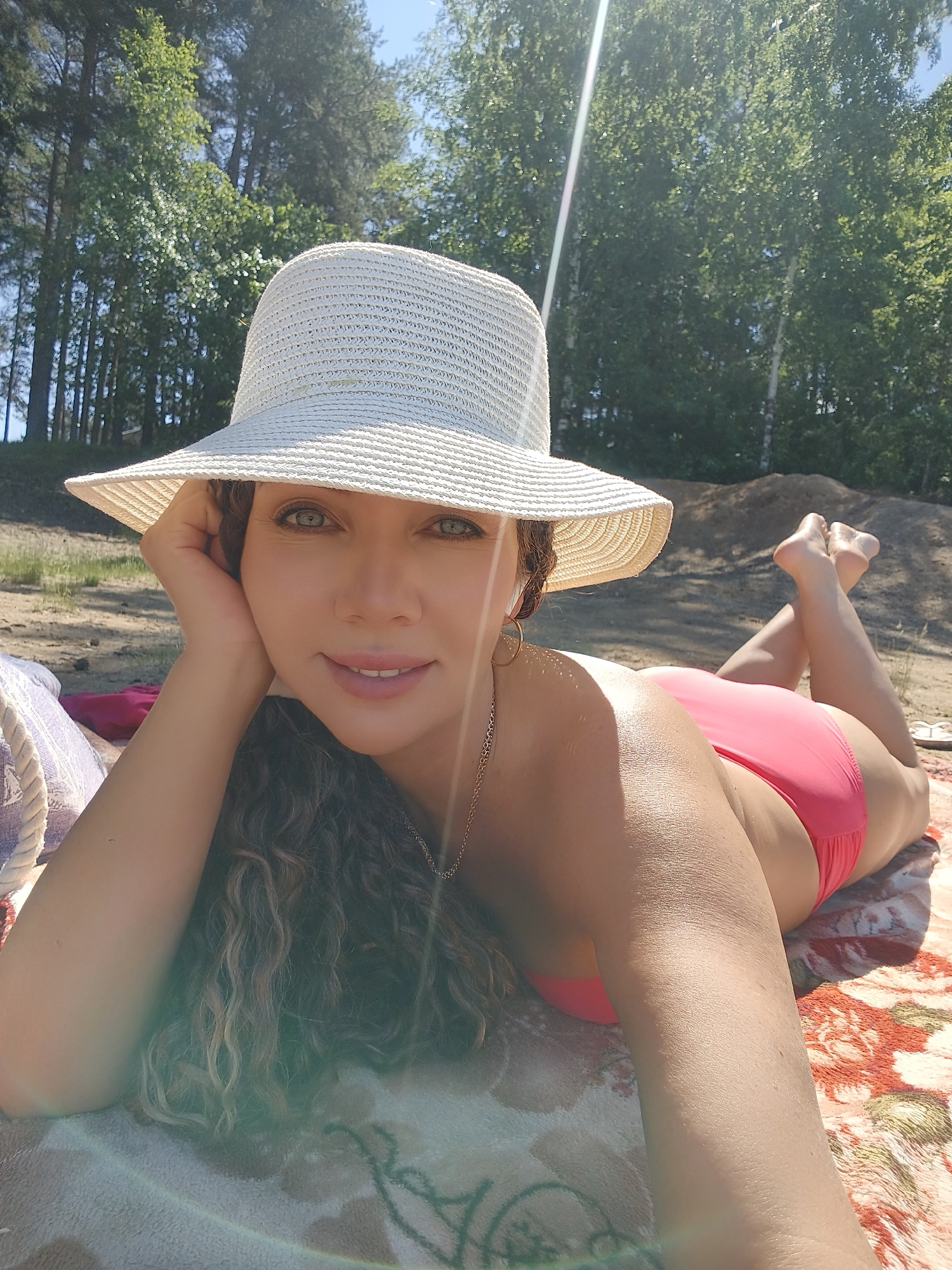 Woman enjoys sunny beach day in pink bikini and straw hat