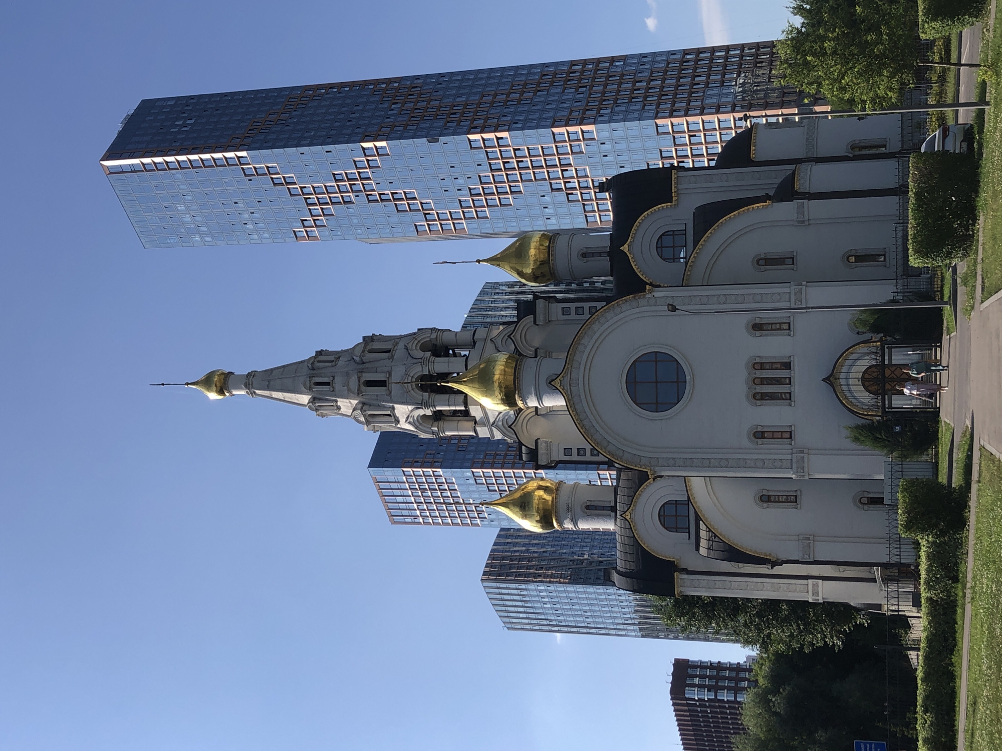 Orthodox church with golden domes against a modern glass skyline