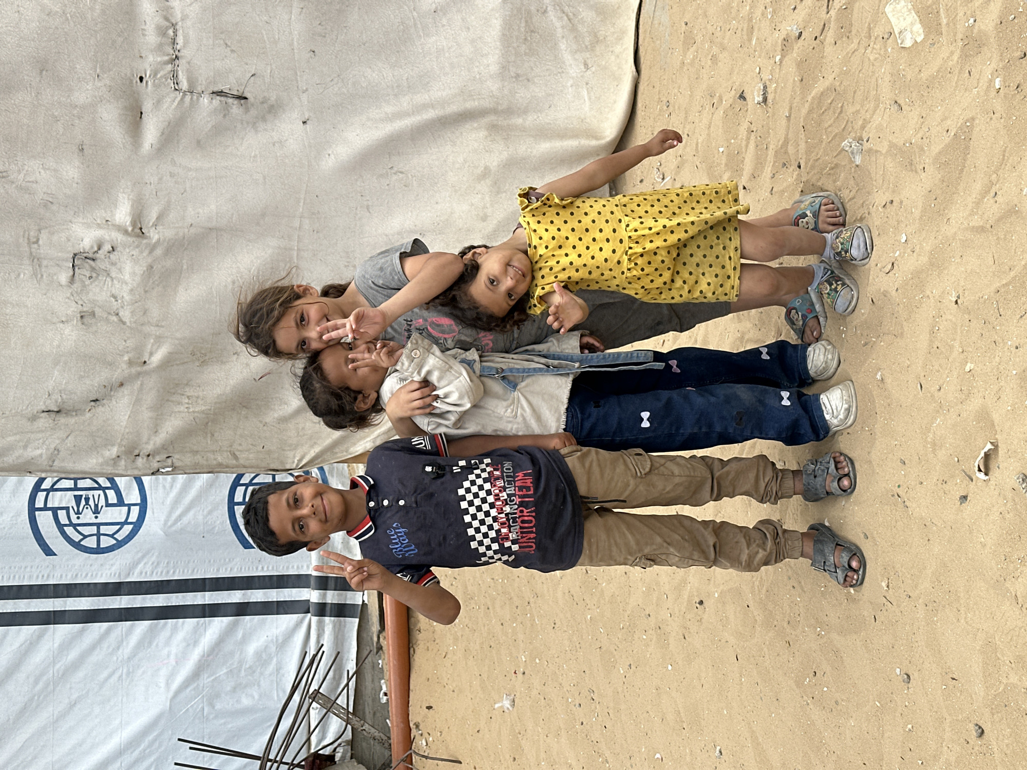 Four children lying together in sandy area in Gaza