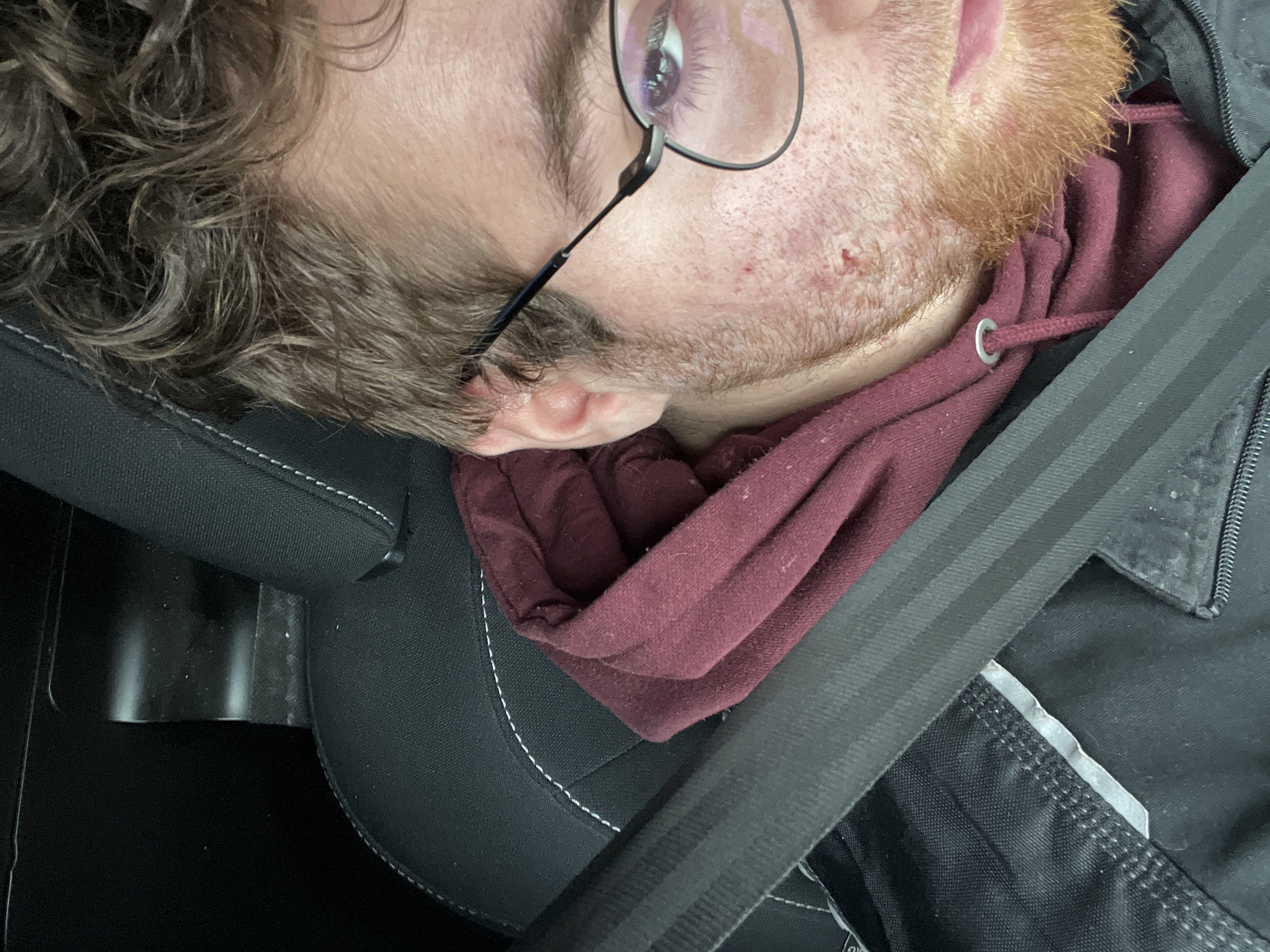 Person rests in car seat during journey in Pernik