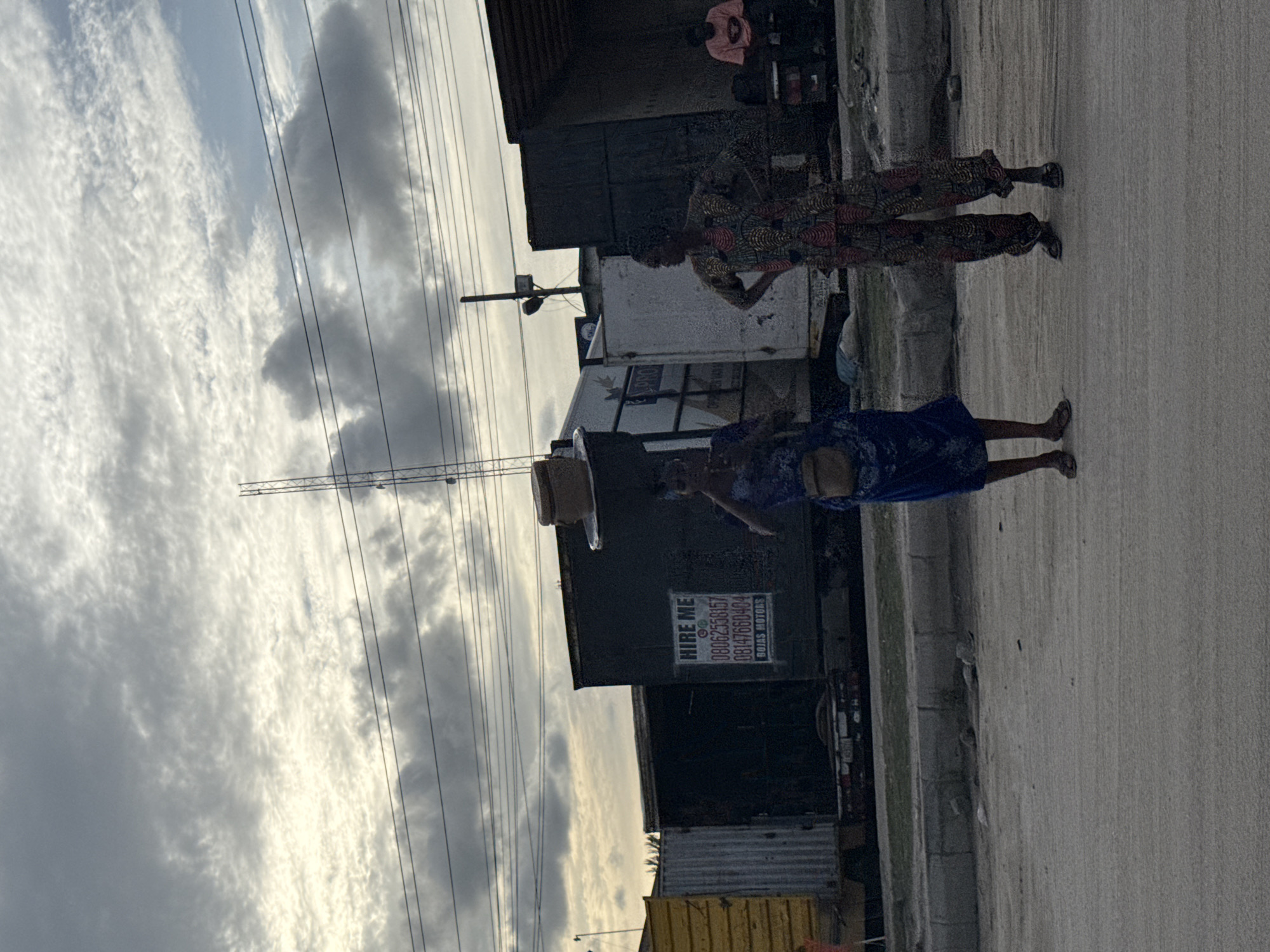 Two women walk roadside in Lagos, one carrying box
