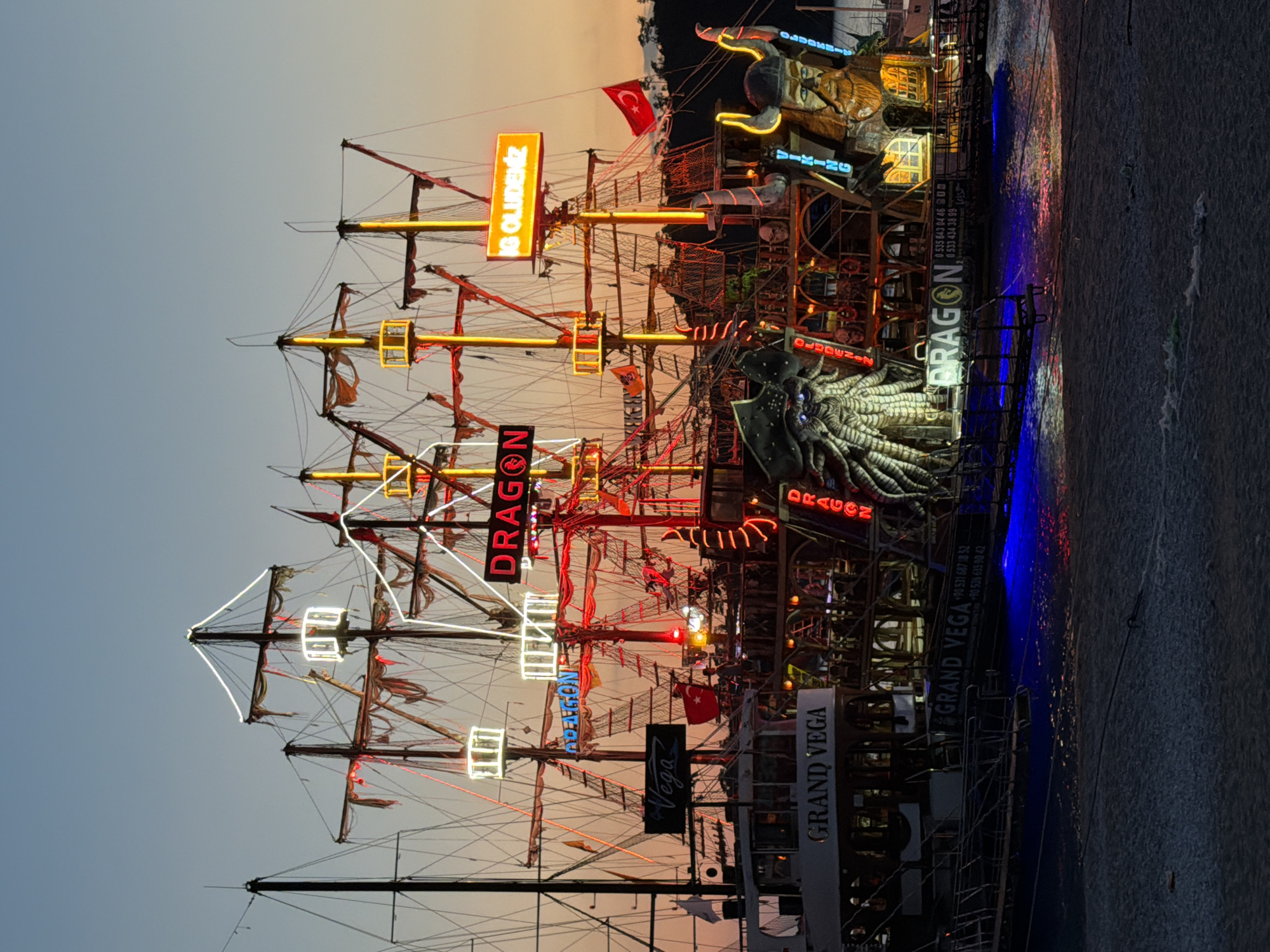 Illuminated tourist ships dock at Fethiye harbor during evening