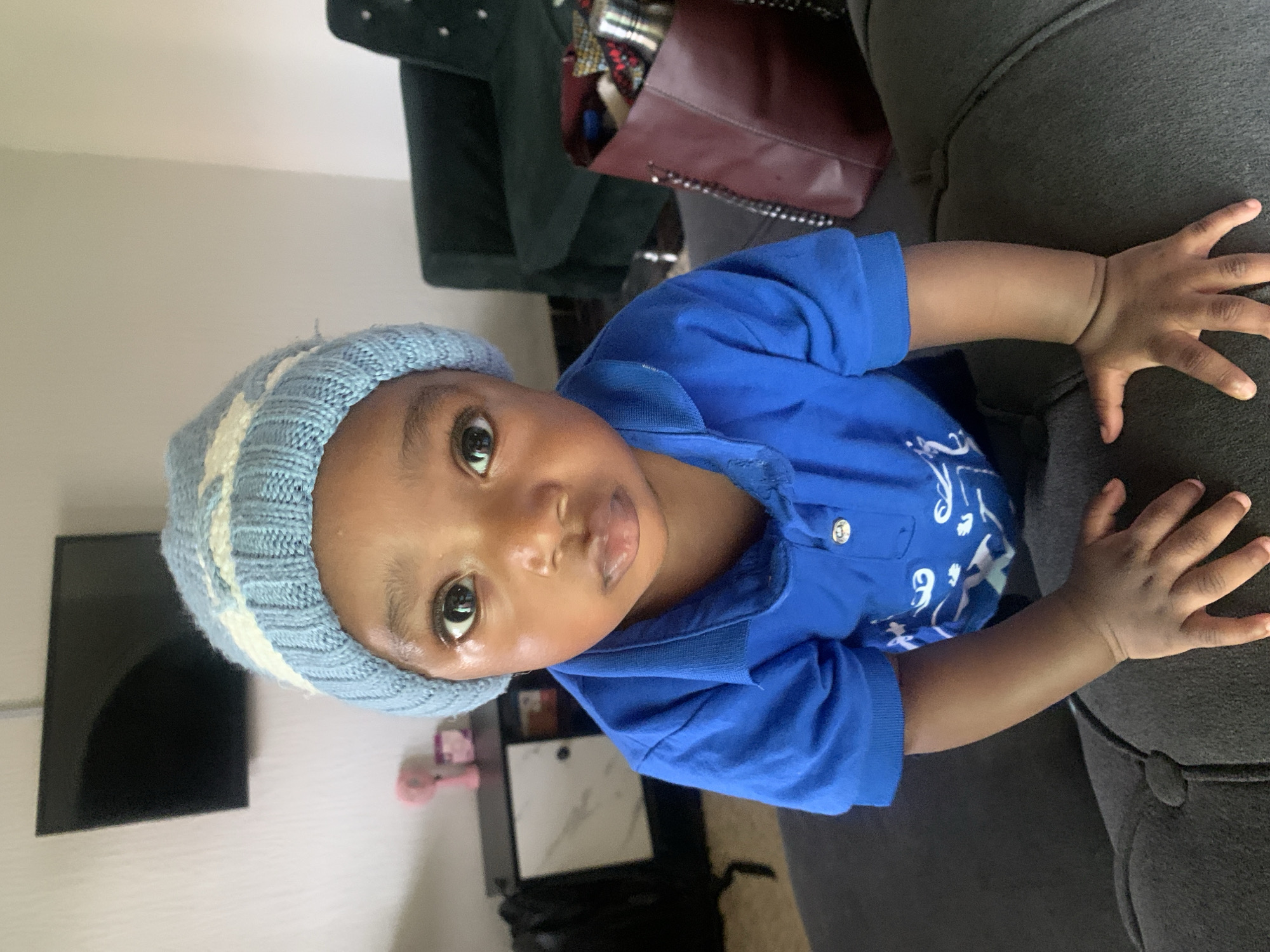 Small child in blue beanie plays around a home in Nigeria