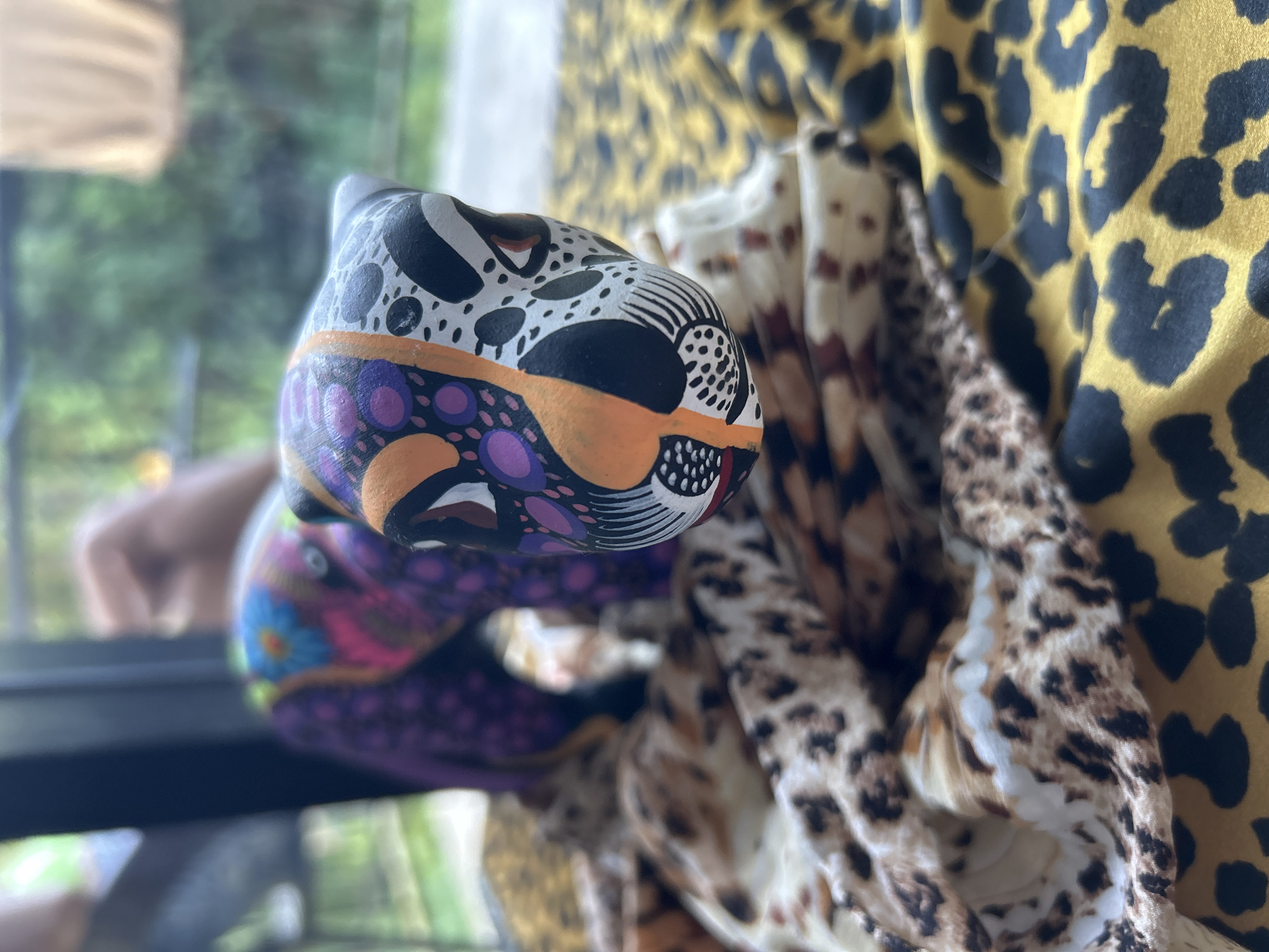 Vibrant wooden cat sculpture spotted on patterned fabric in Thailand