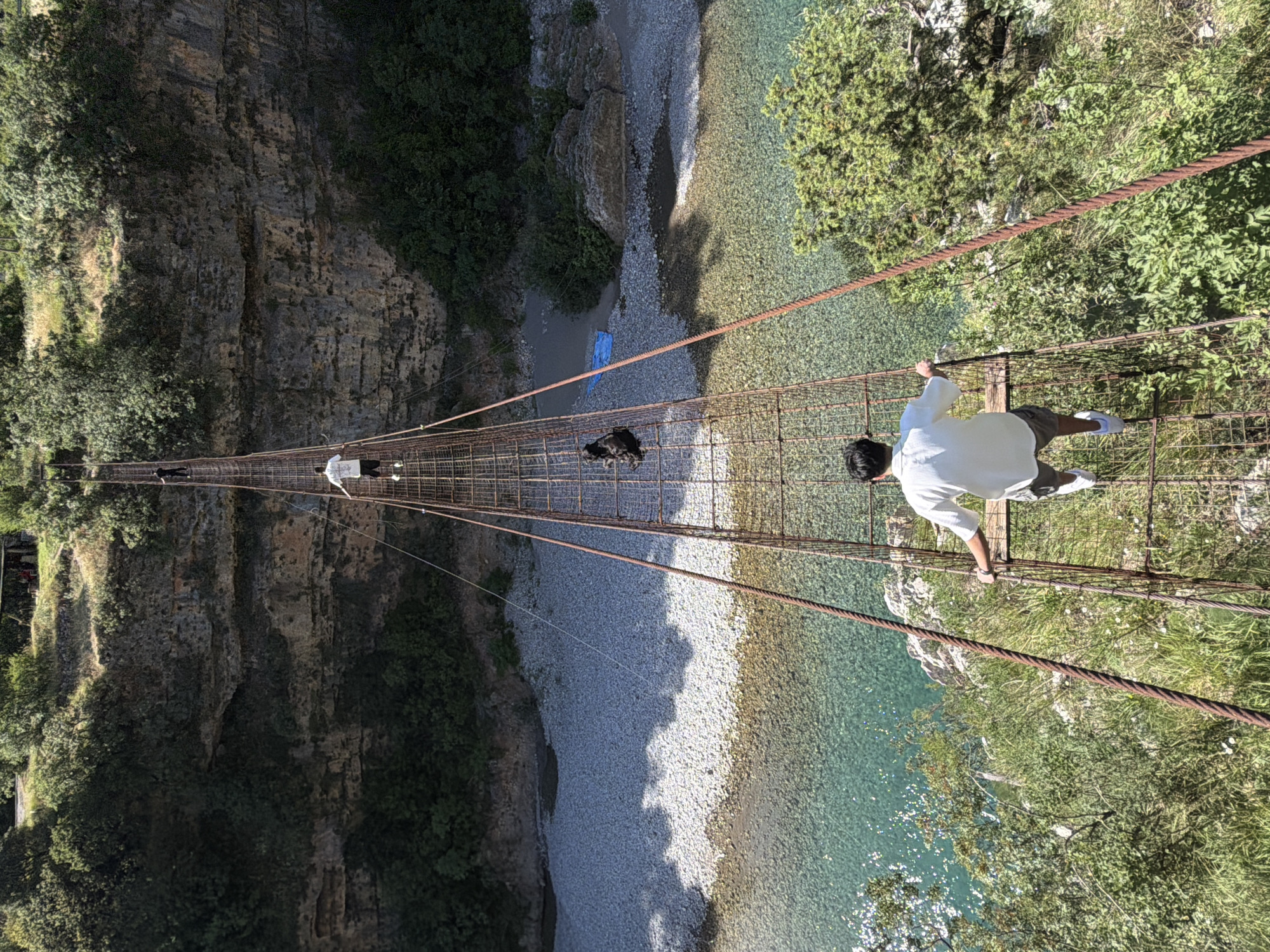 Tourists cross rustic suspension bridge over Montenegro river gorge