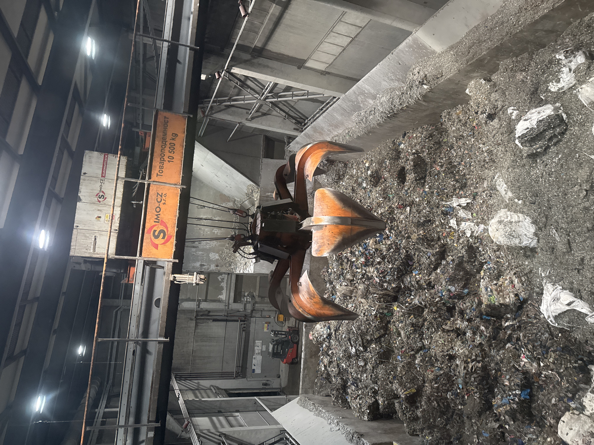 Excavator processes mixed waste pile at Bulgarian industrial site