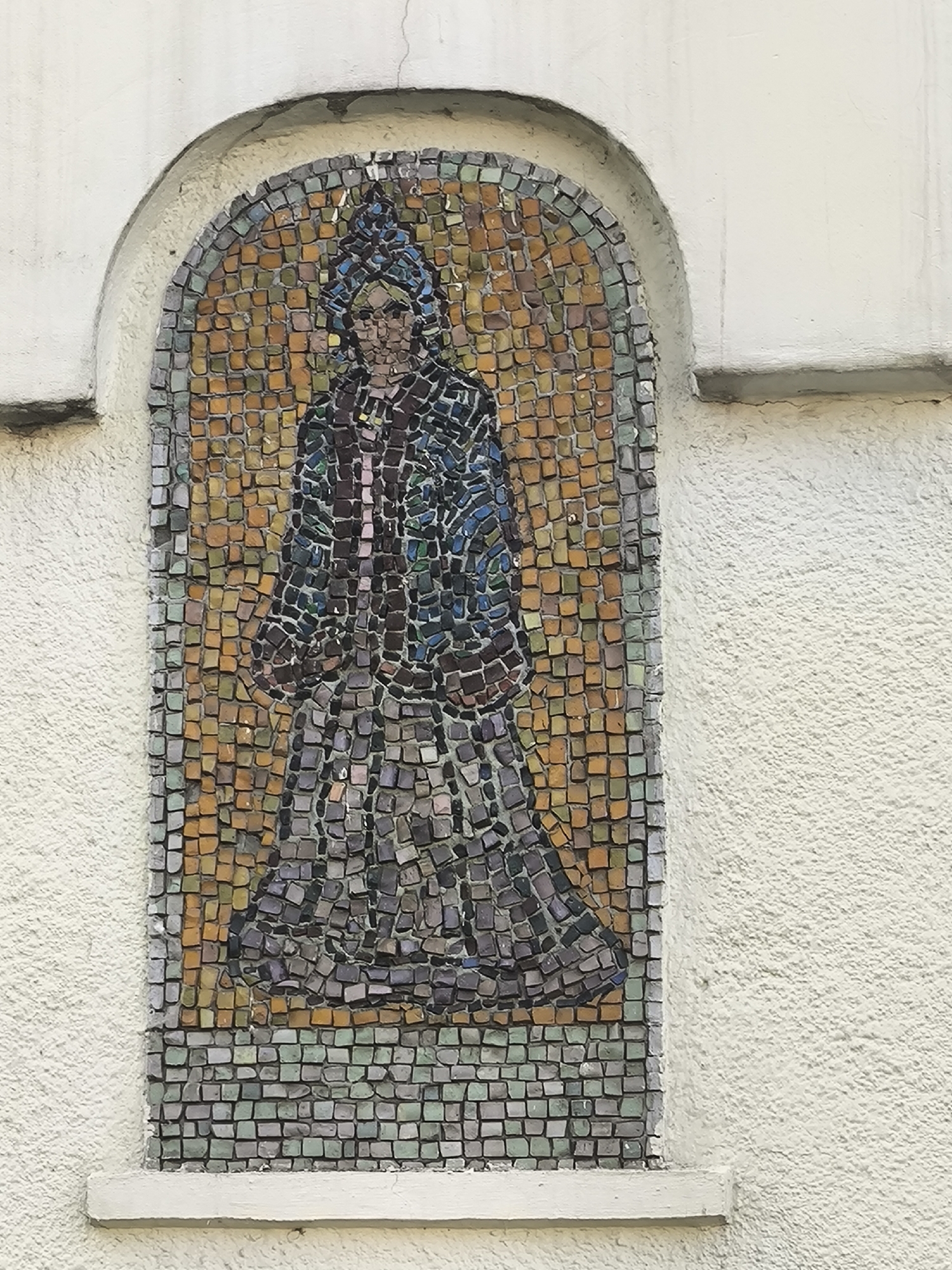 Ornate mosaic facade with robed figures and landscape murals