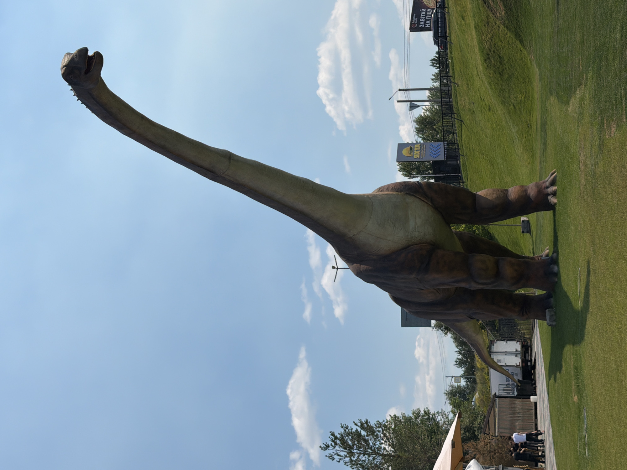 Outdoor celebration in Khotianivka park with dinosaur statues nearby