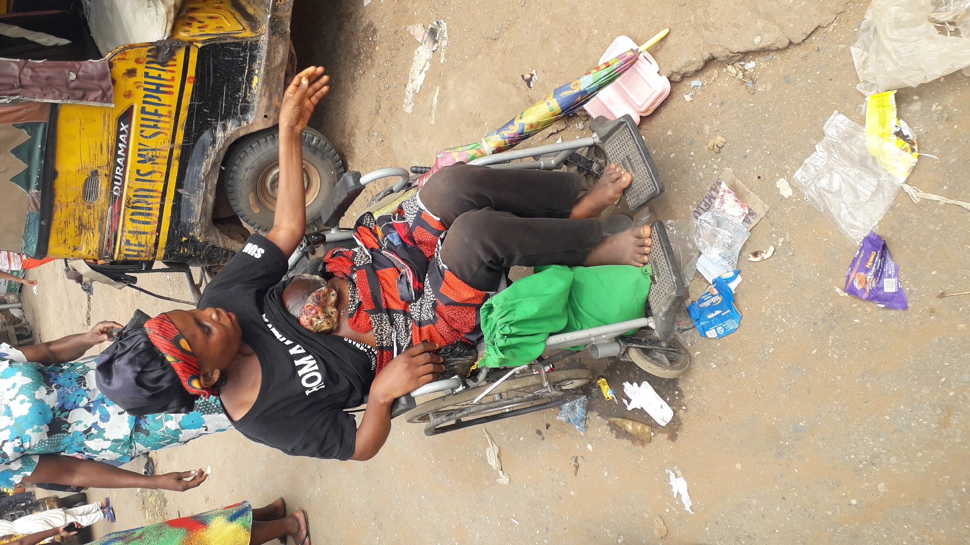 Street scene observed in Nkpor, Nigeria with wheelchair-bound woman