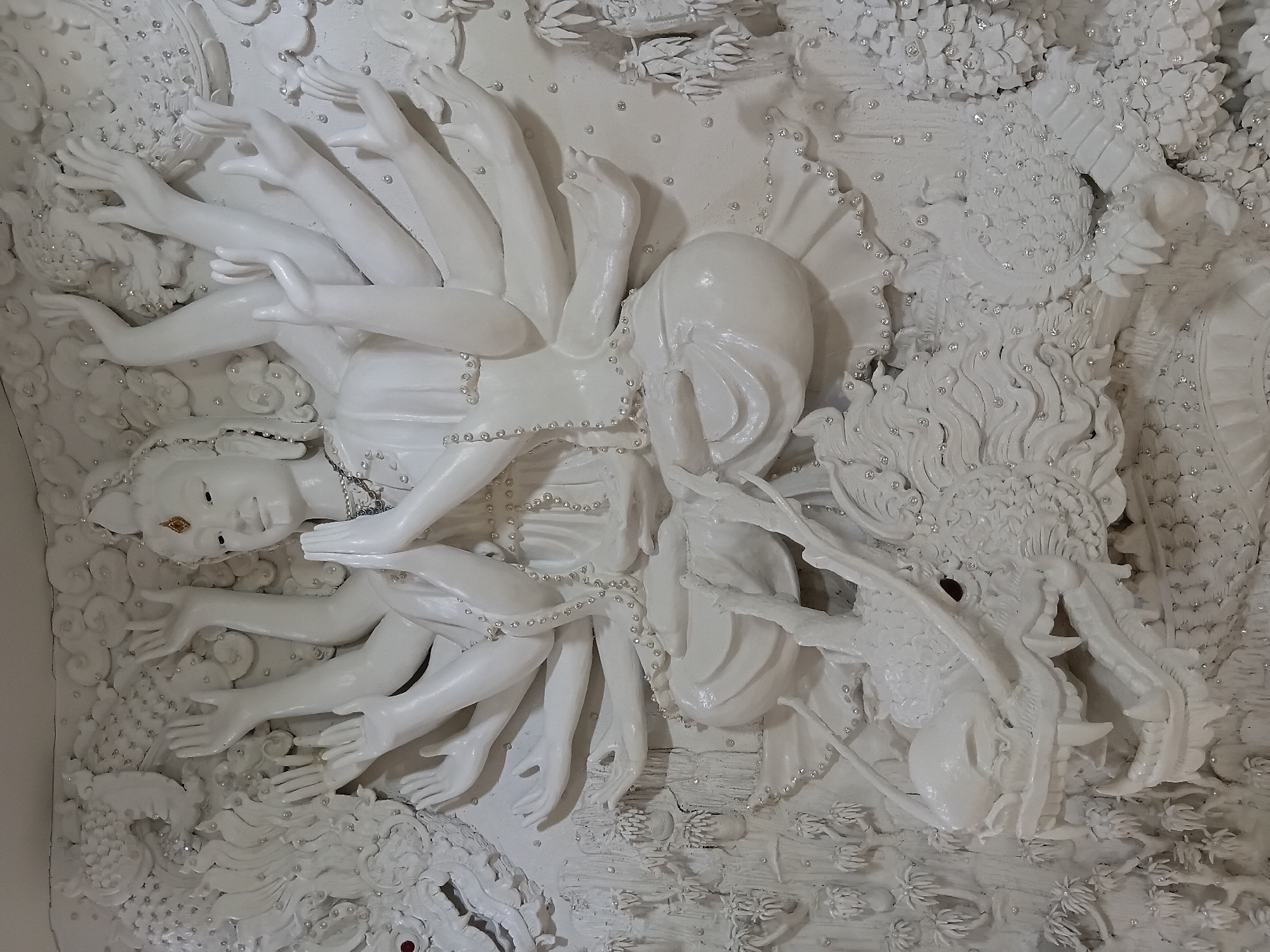 Intricate white relief sculptures fill a Buddhist temple interior