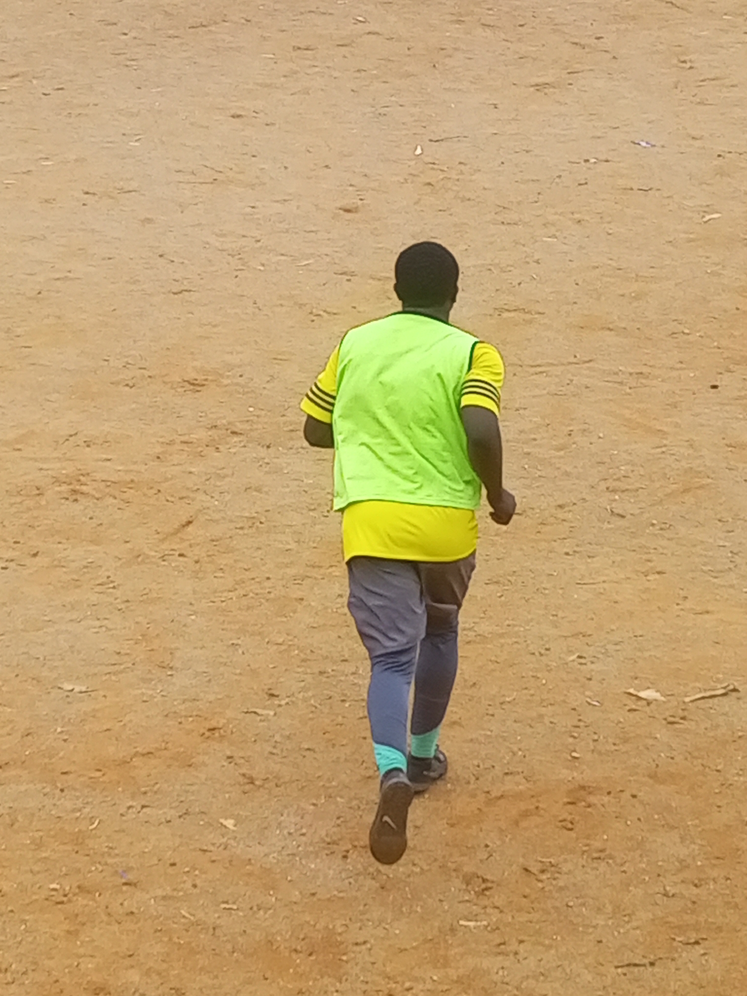Pickup football session on a rocky dirt field in Jos