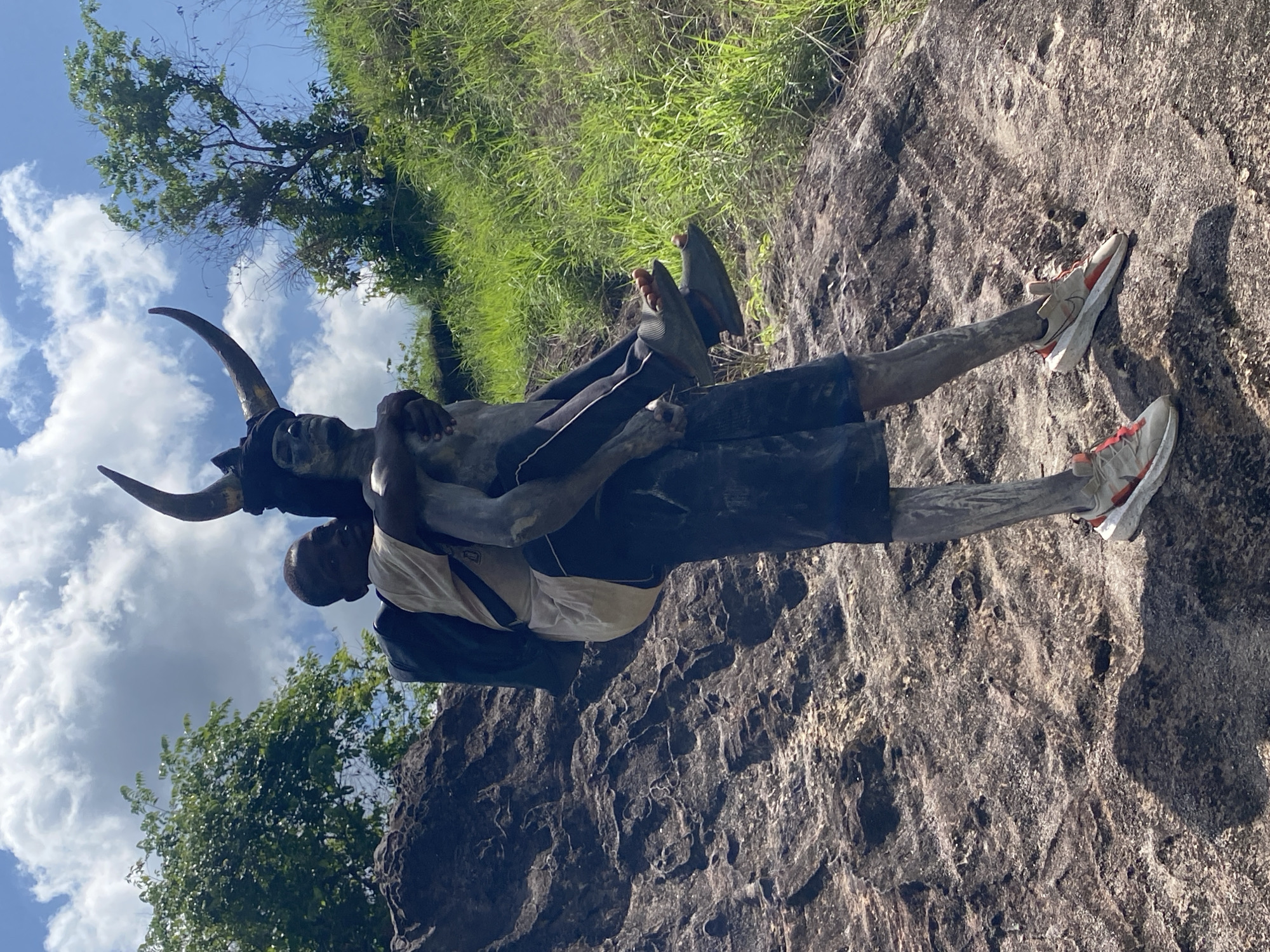 Gray-painted man gives boy piggyback ride in Afikpo