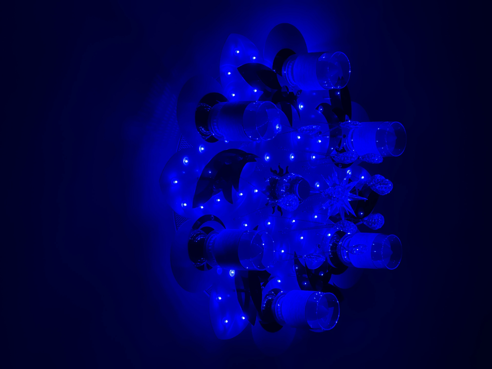 Decorative chandelier with glass cylinders observed emitting colored light