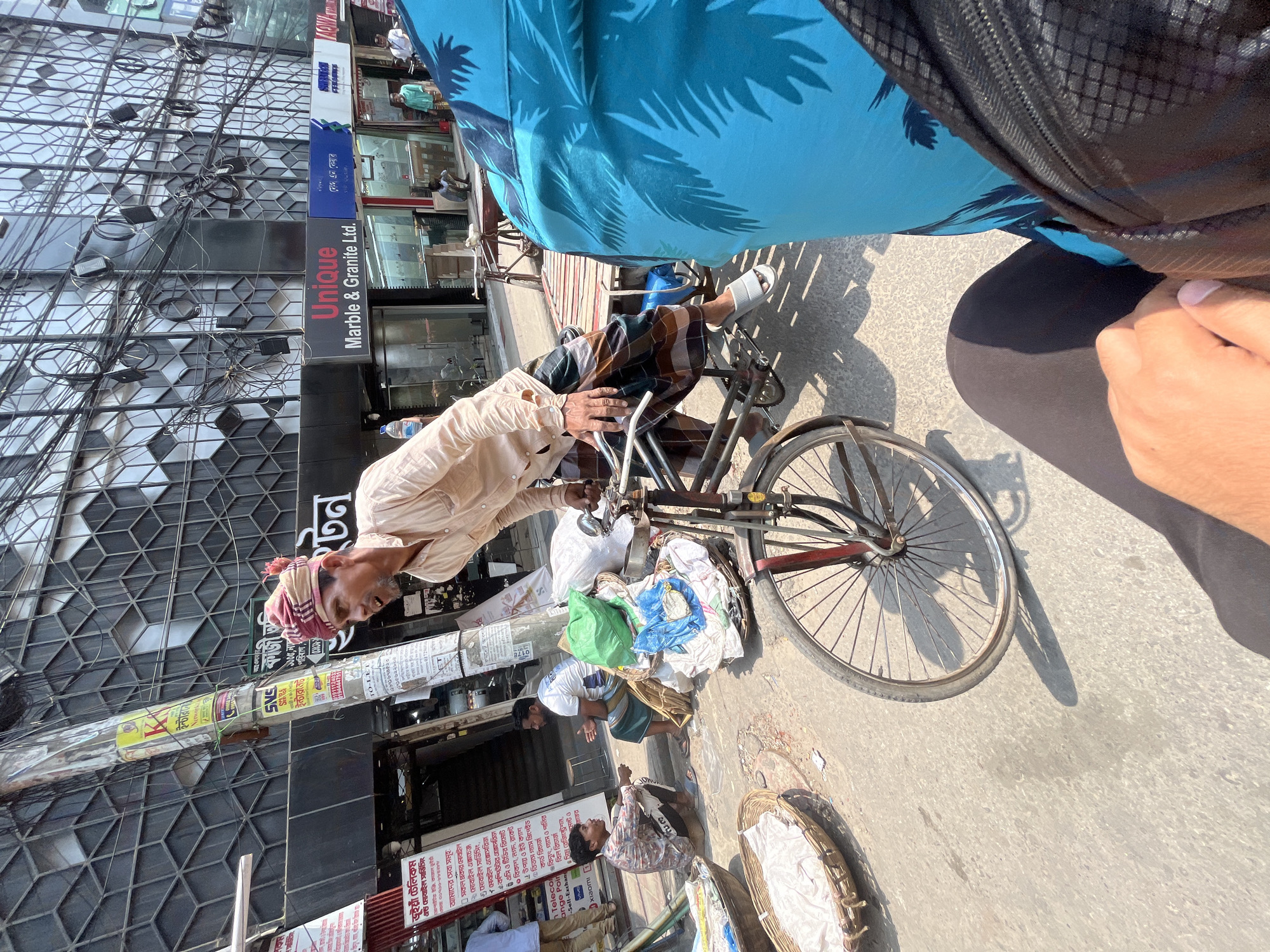 Elderly cyclist transports textiles through Dhaka streets