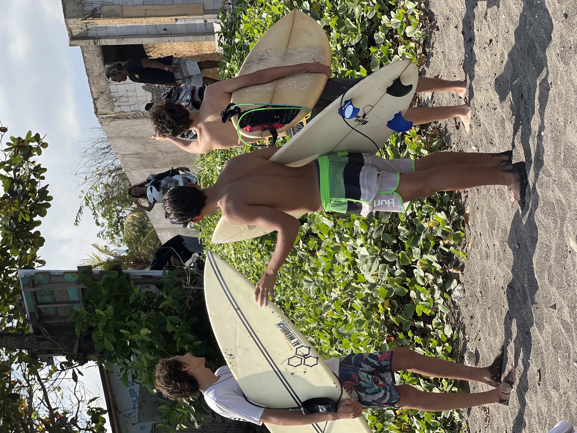 Surfers and beachgoers on Mengwi's volcanic sand coast