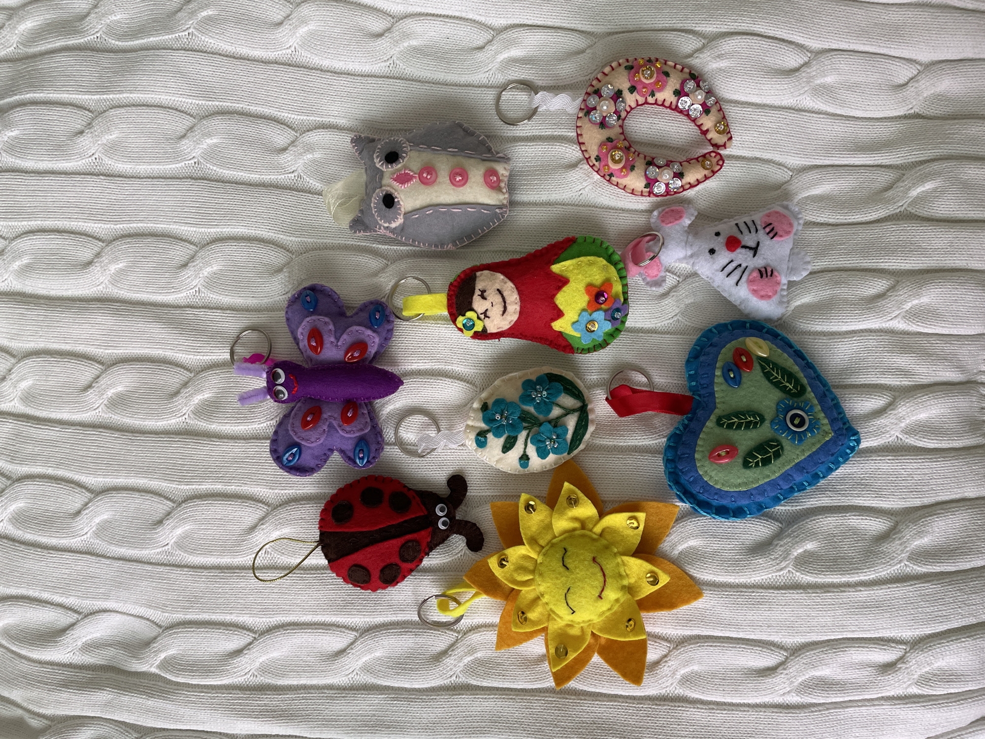 Handmade felt keychains displayed on knitted fabric in Sharapovo