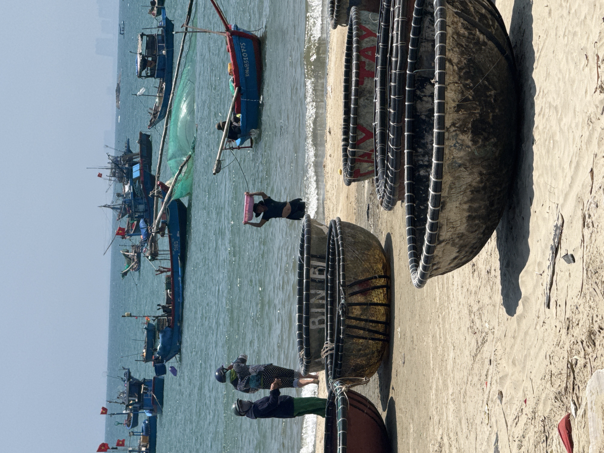 Traditional fishing boats and drying catch on Đà Nẵng beach