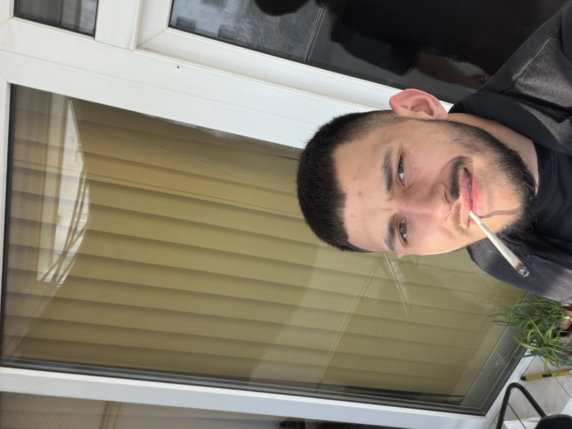 Man smoking cigarette by window in Sliven, Bulgaria