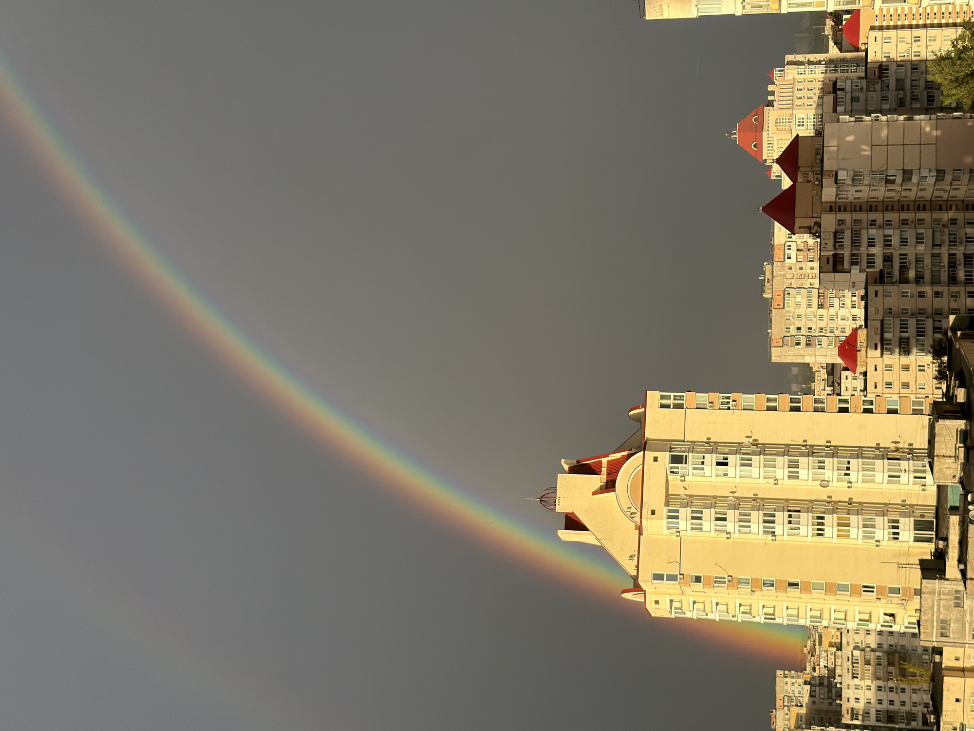 Double rainbow over Kyiv's apartment skyline on a grey afternoon