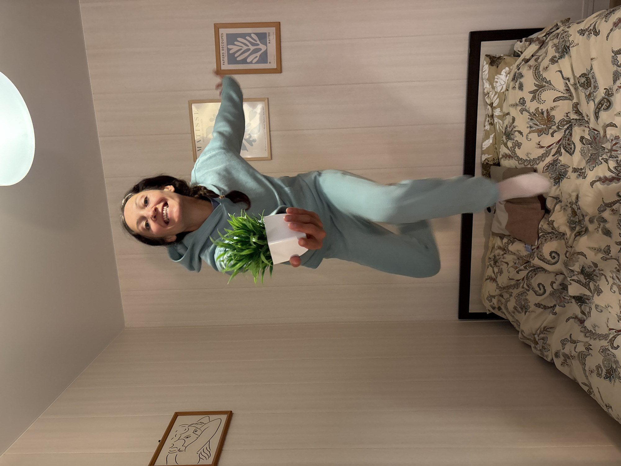 Woman jumps joyfully indoors holding plant in Gelendzhik