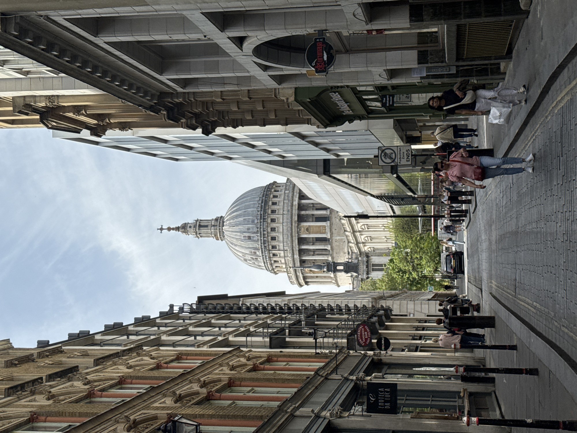 Pedestrians stroll London cobblestone street with St. Paul's Cathedral backdrop