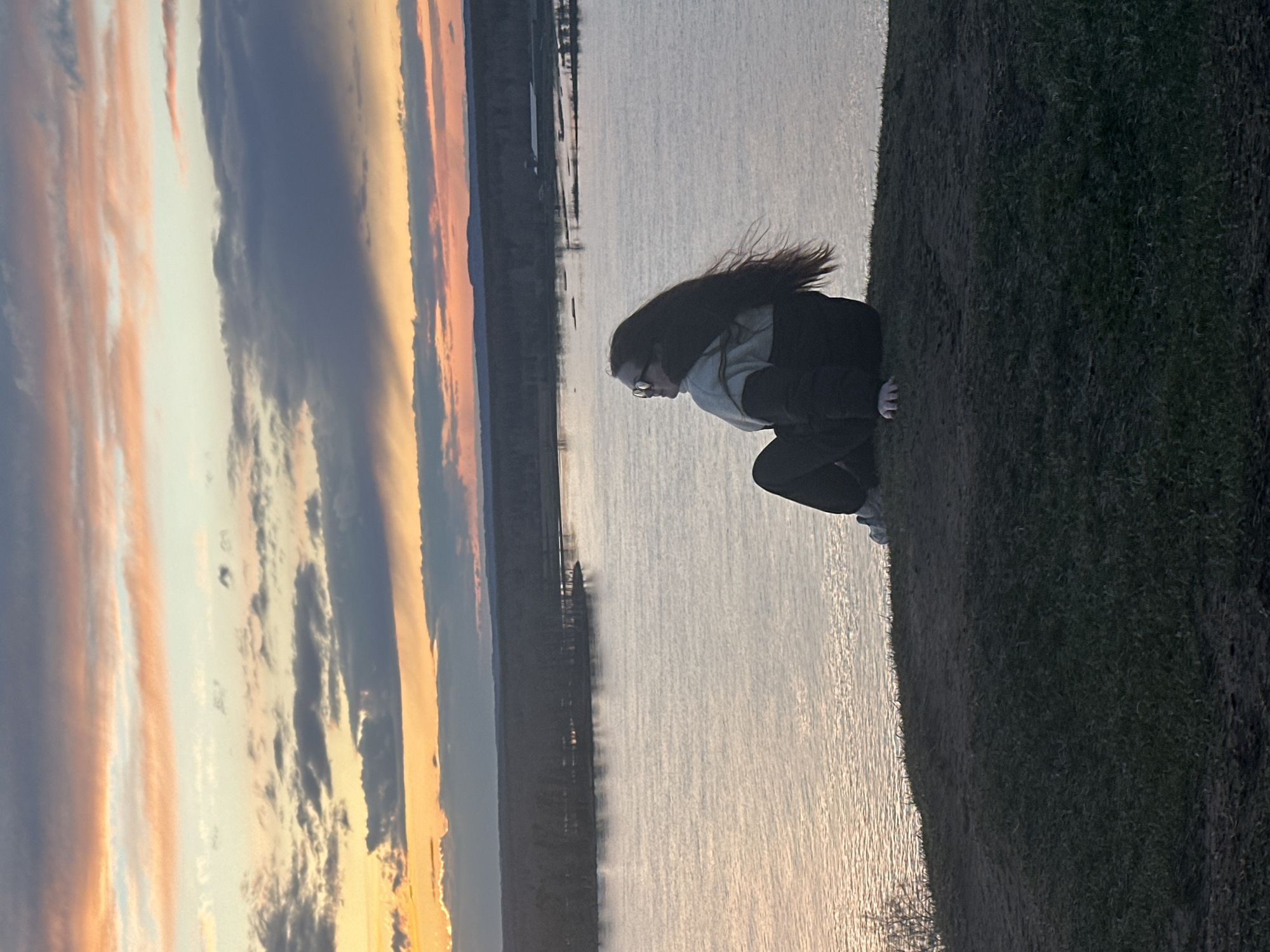 Person watches sunset over water in Ольховка, Russia