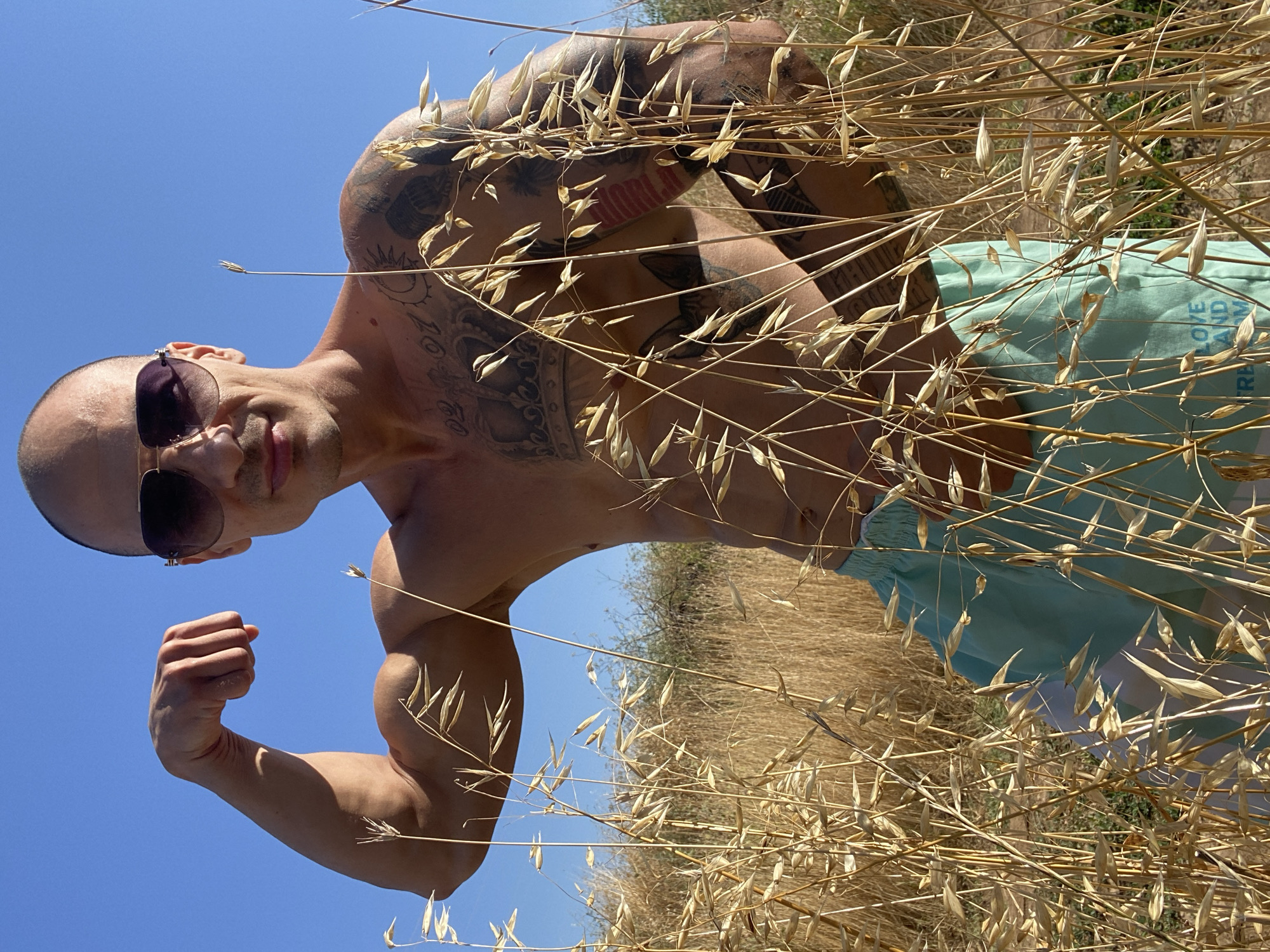 Tattooed figure poses and jumps in a dry Bulgarian field