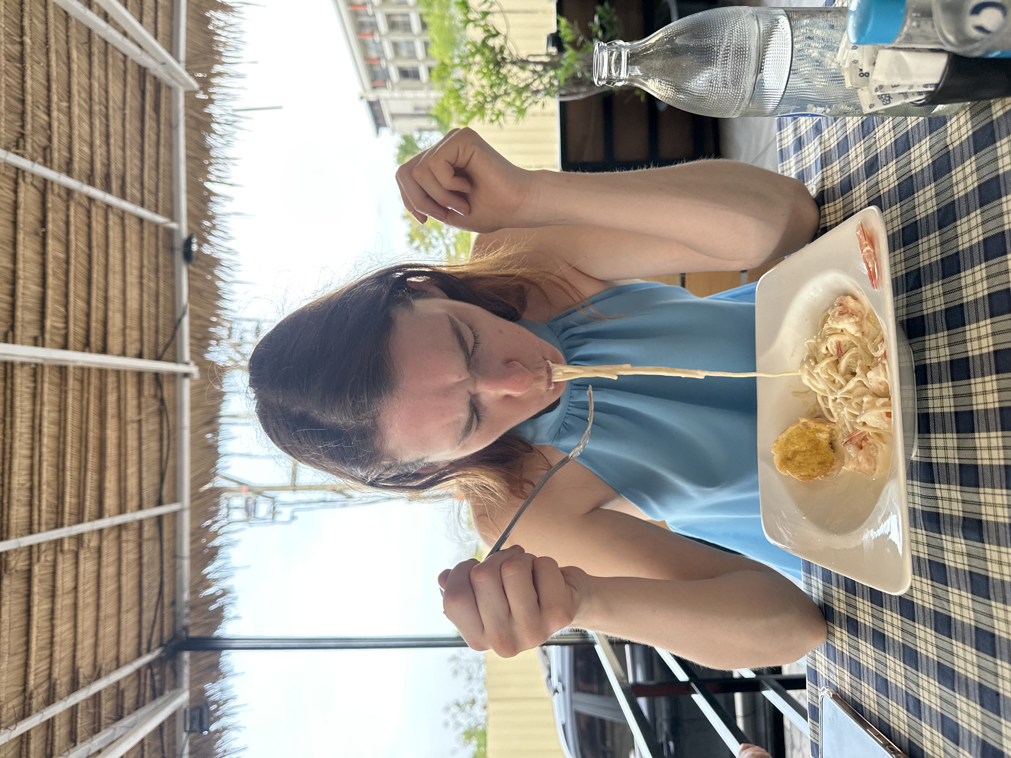 Woman documents pasta meal at outdoor restaurant in Thailand