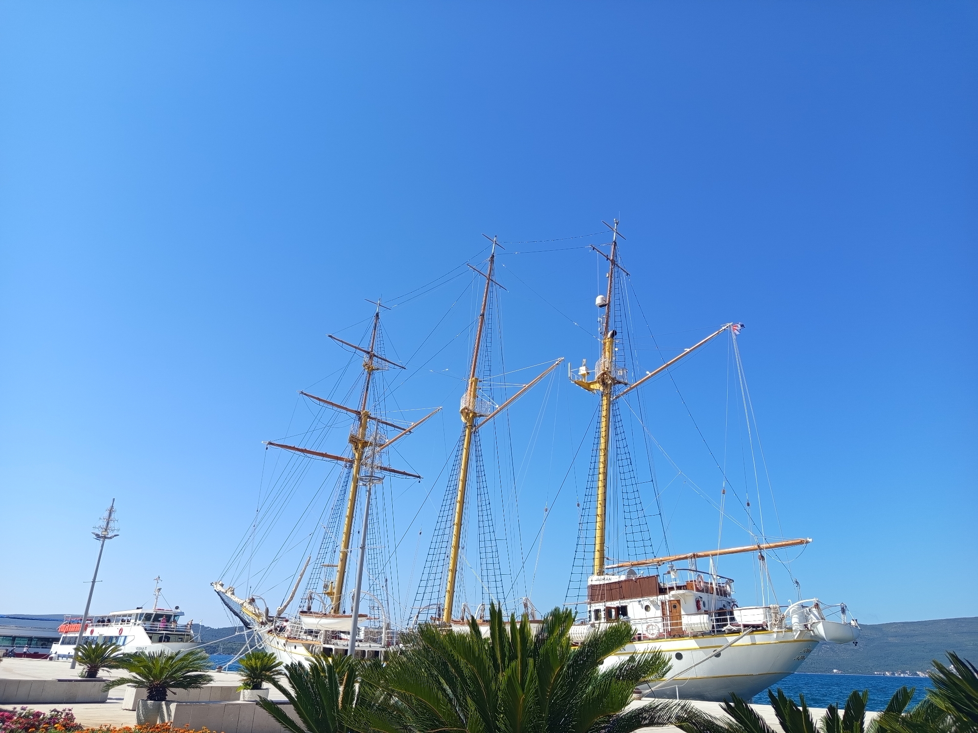 Sunny waterfront day with tall ships, ferries, and urban architecture