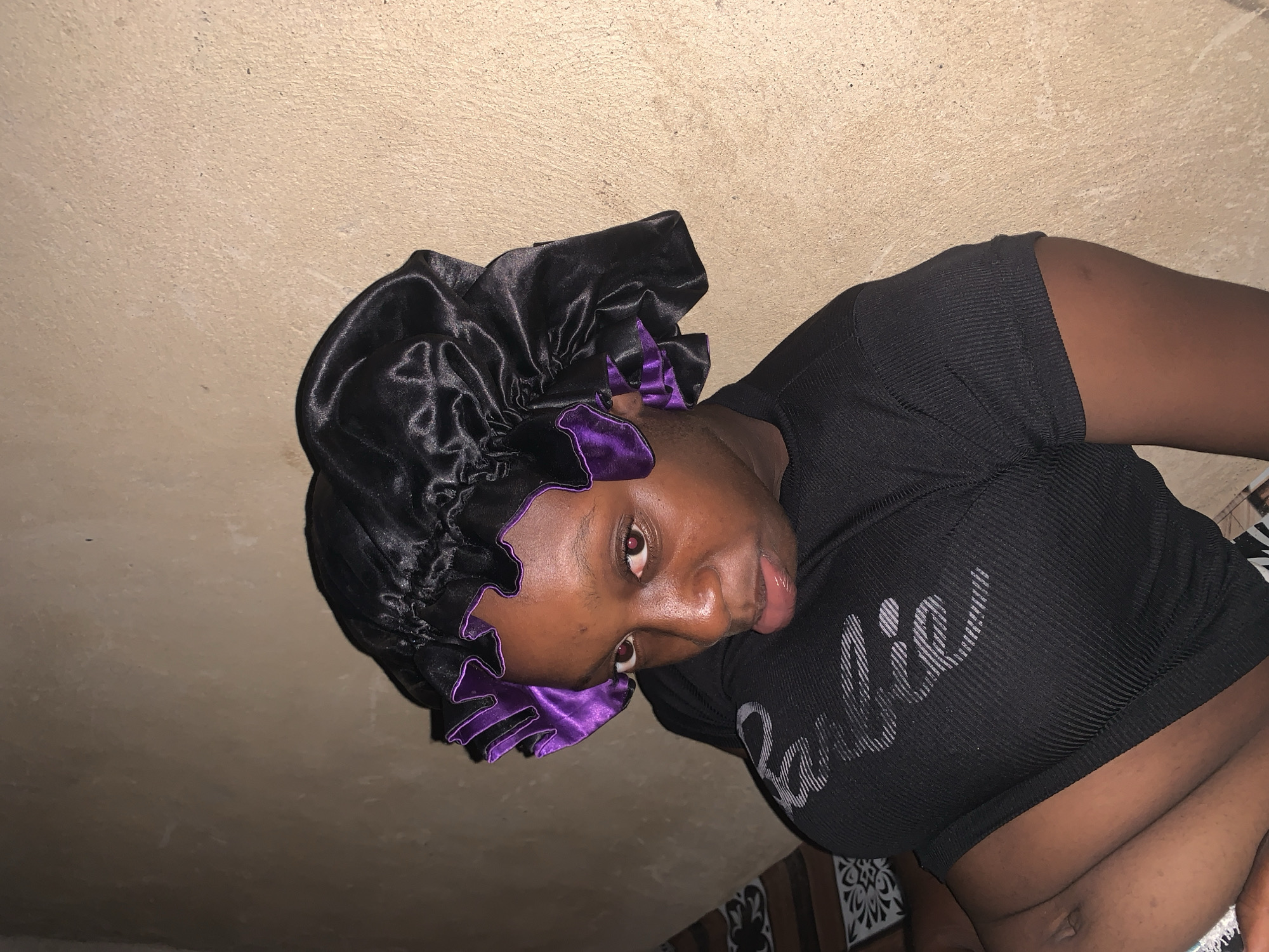 Woman in purple-trimmed bonnet captured smiling indoors