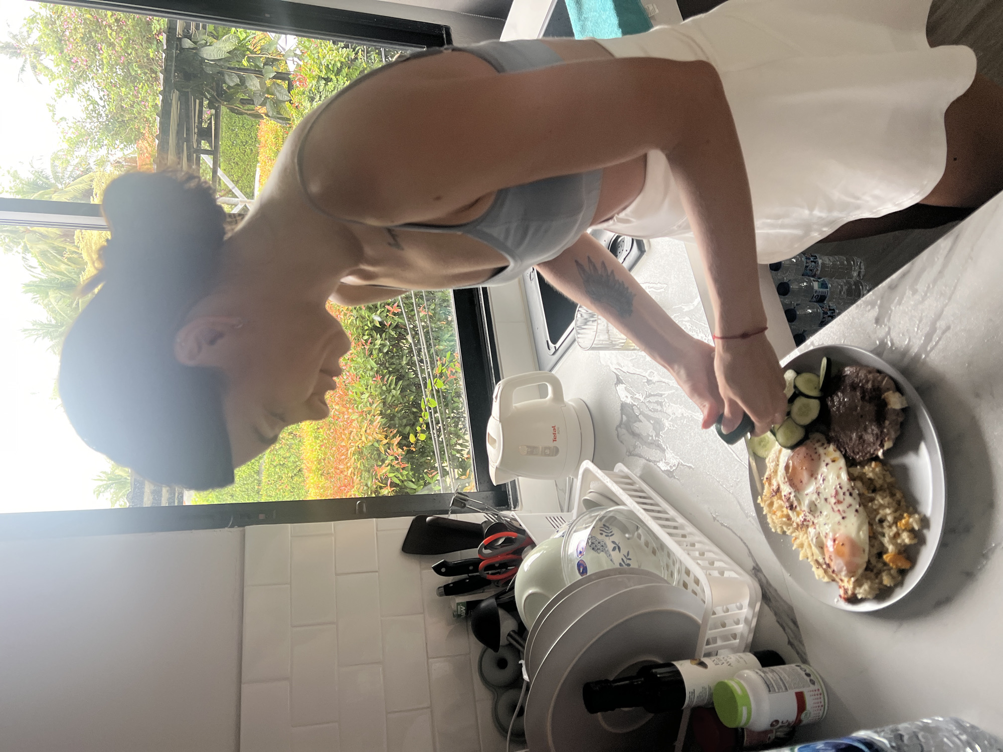 Woman cooks breakfast with fried eggs in Thai kitchen