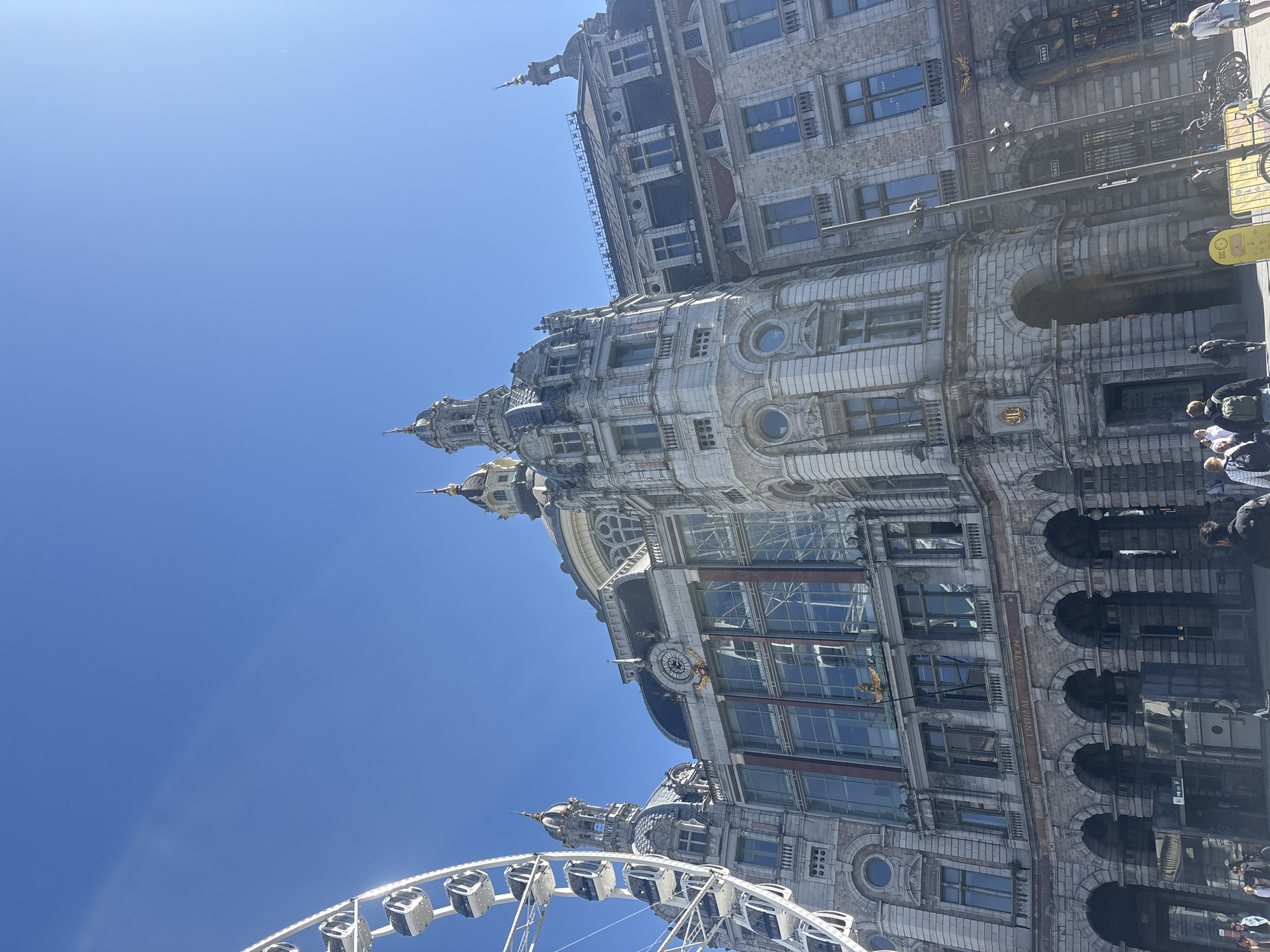 Historic Antwerp Central Station contrasts with modern Ferris wheel