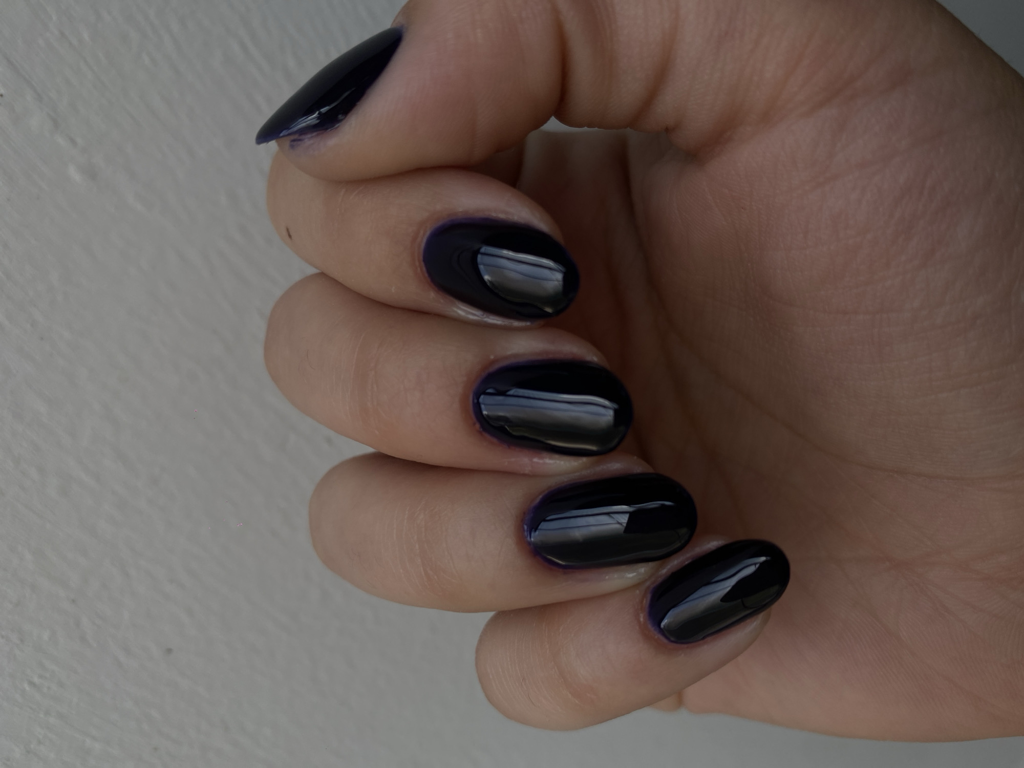 Woman's manicured hand with dark polish observed in close-up