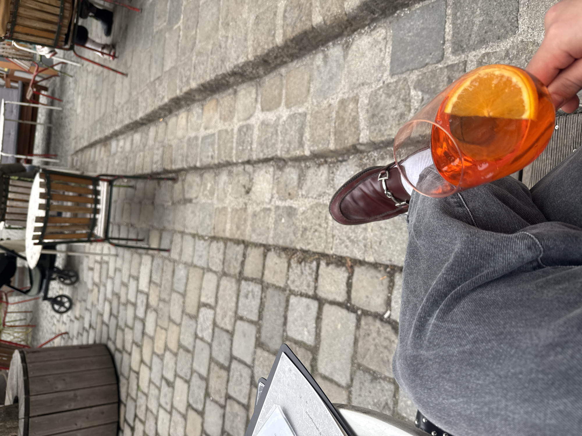Person enjoys orange cocktail at Vienna restaurant table