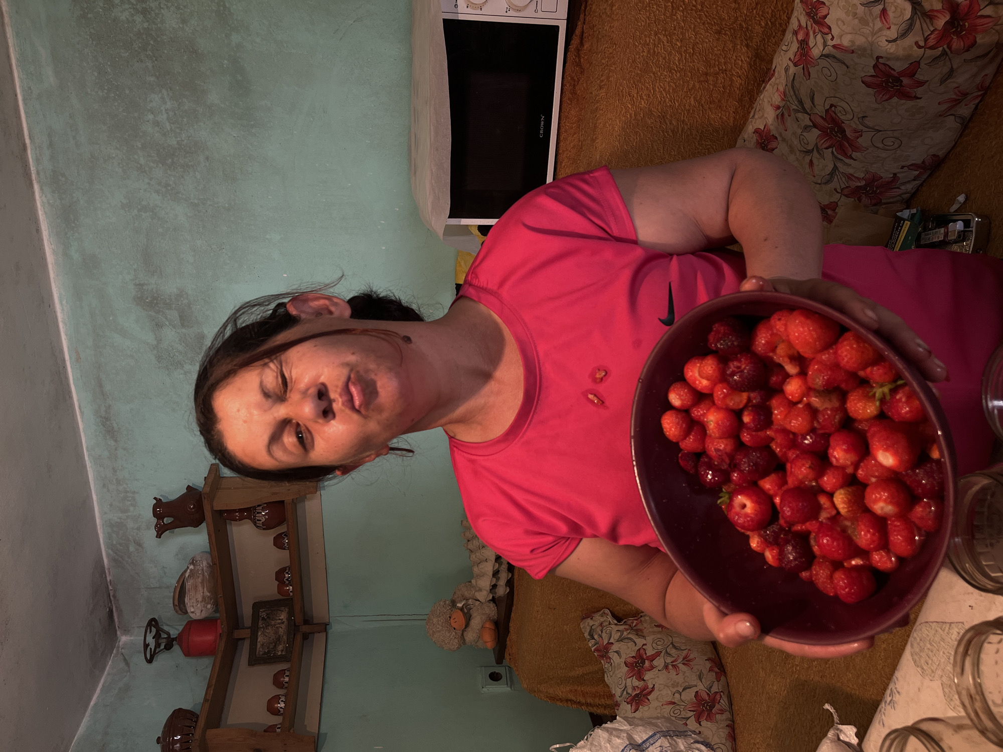 Woman prepares traditional strawberry compote in Bulgarian village kitchen