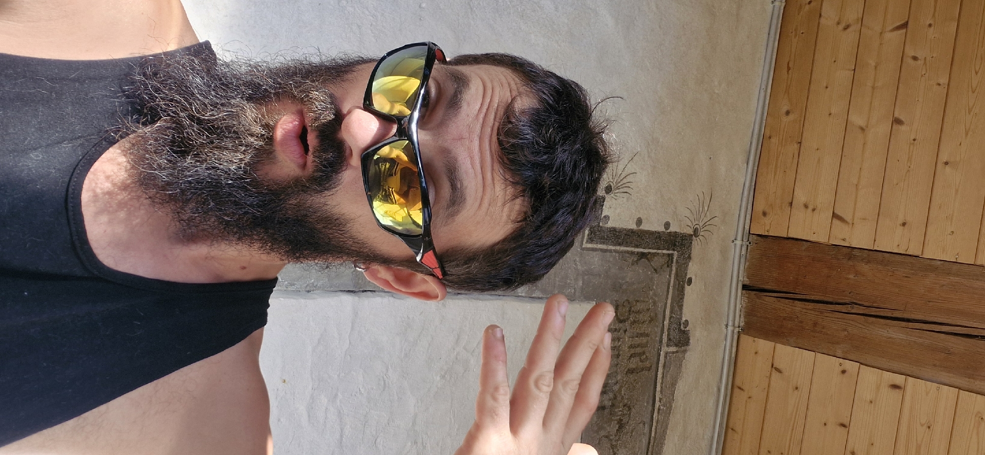 Shielding eyes from the sun outside a mural wall in Wattenwil