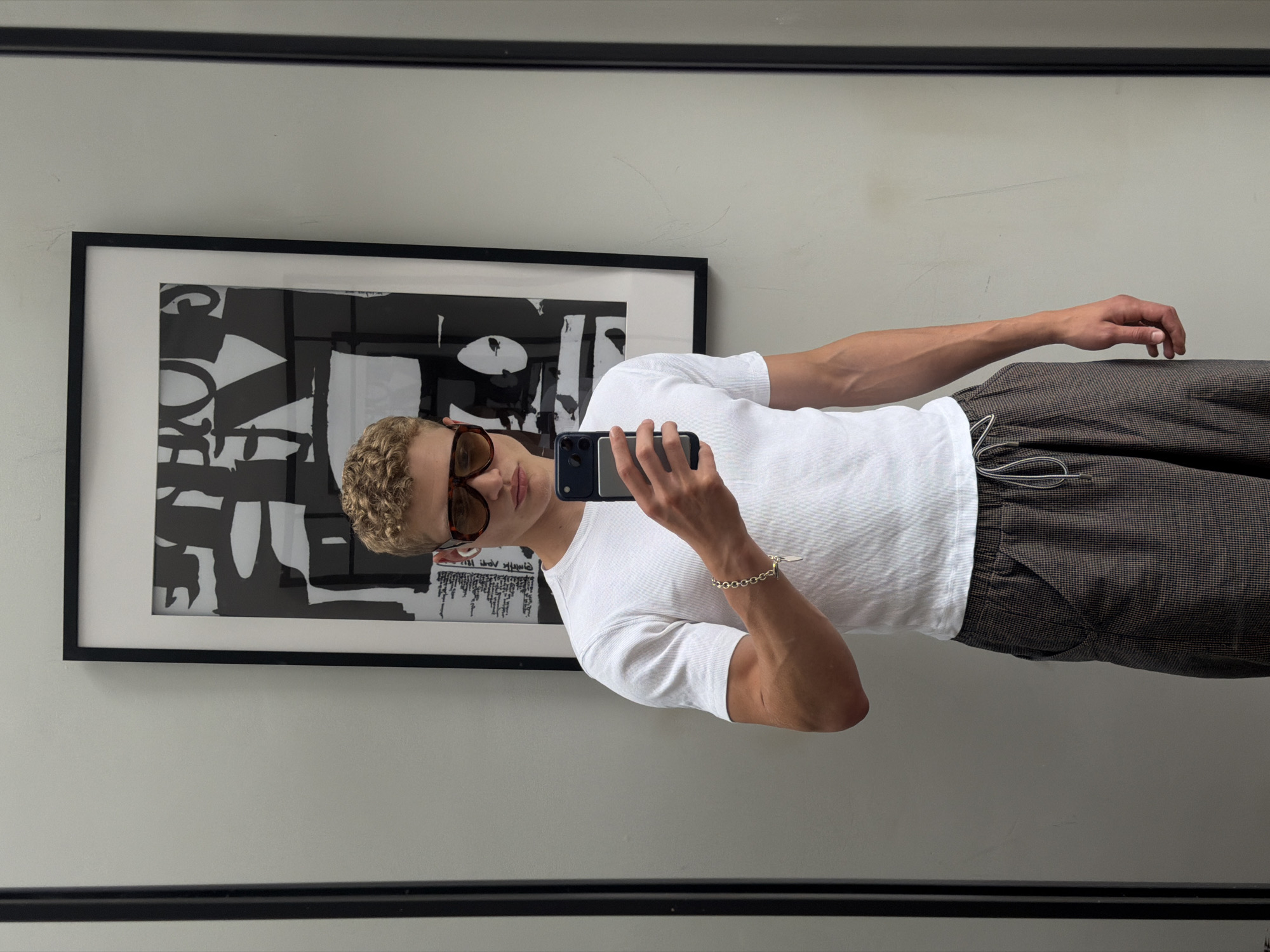 Mirror selfie in a London home, checkered trousers and white tee