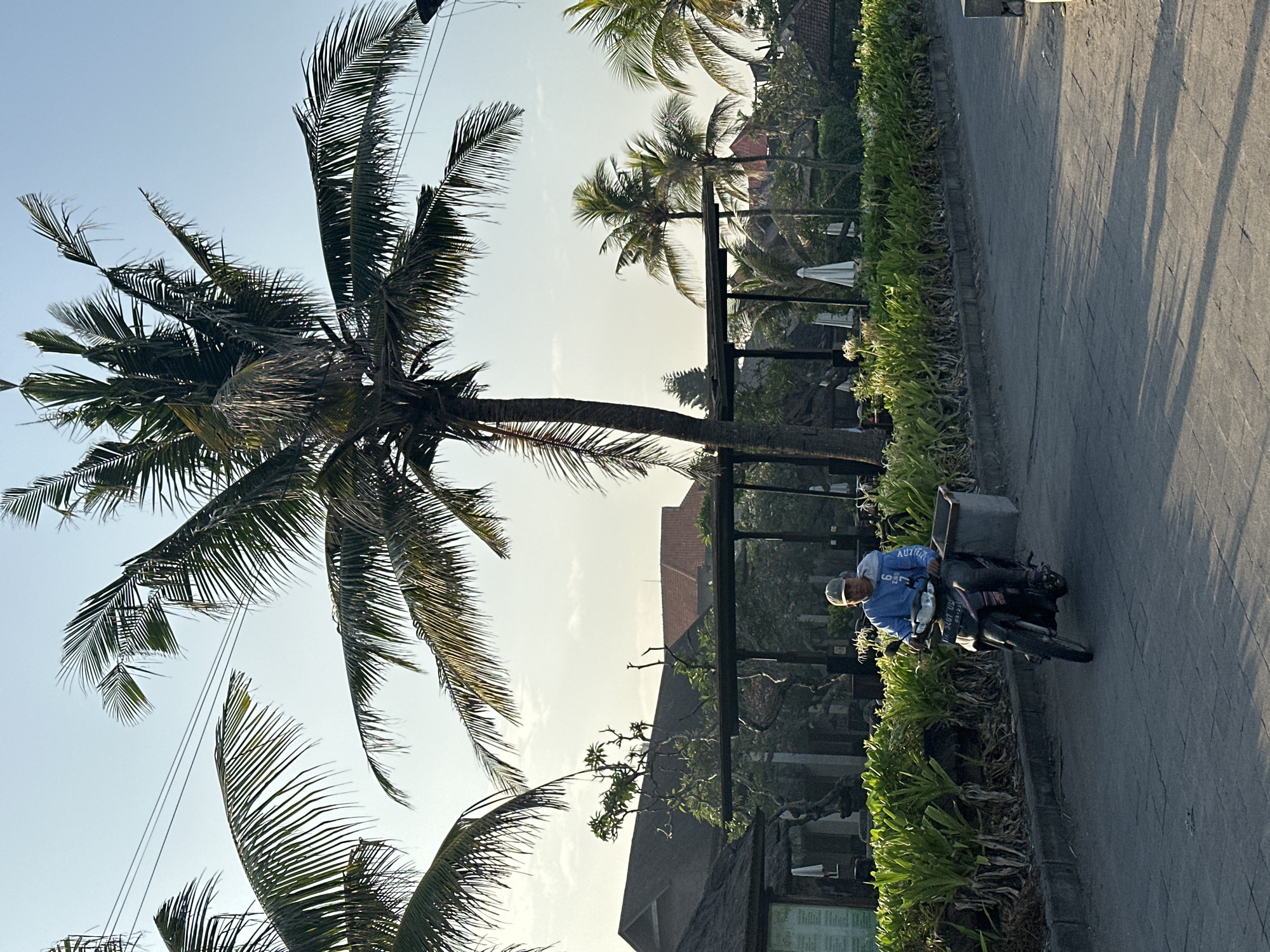 North Kuta beachfront: statue, sand, and motorbike activity