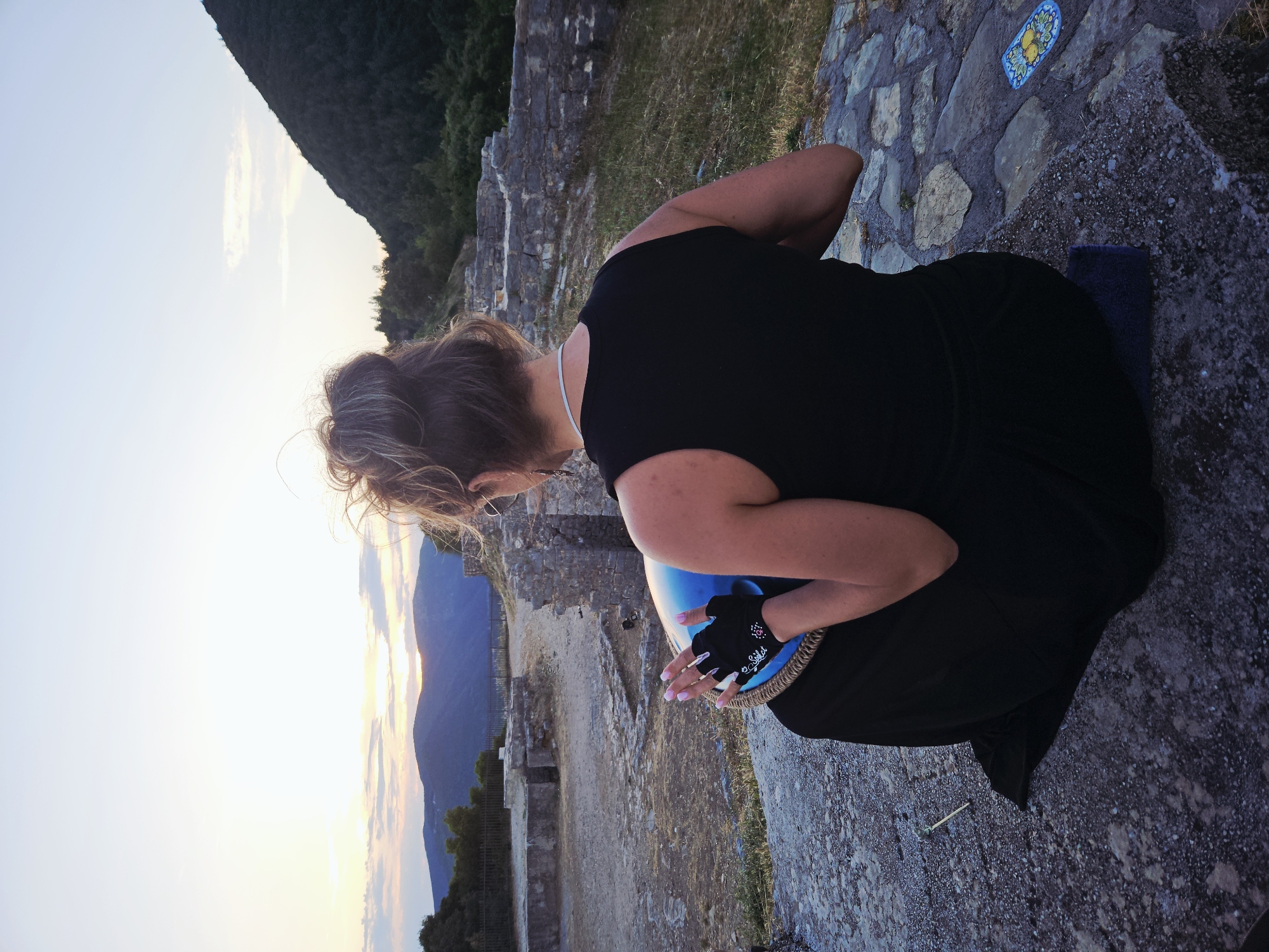 Woman plays handpan during sunset at ancient stone location