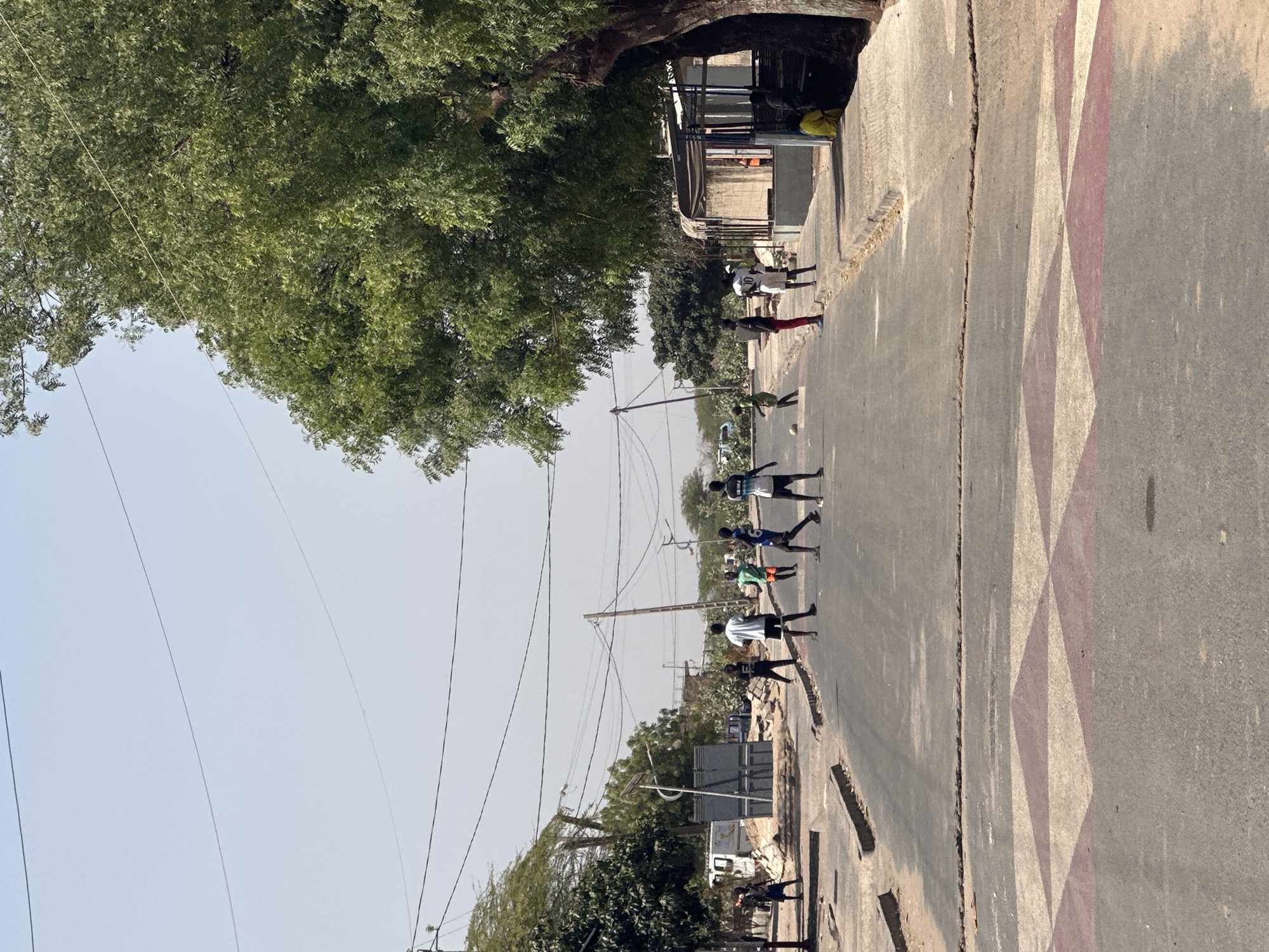 People walk down patterned street in rural Senegal community