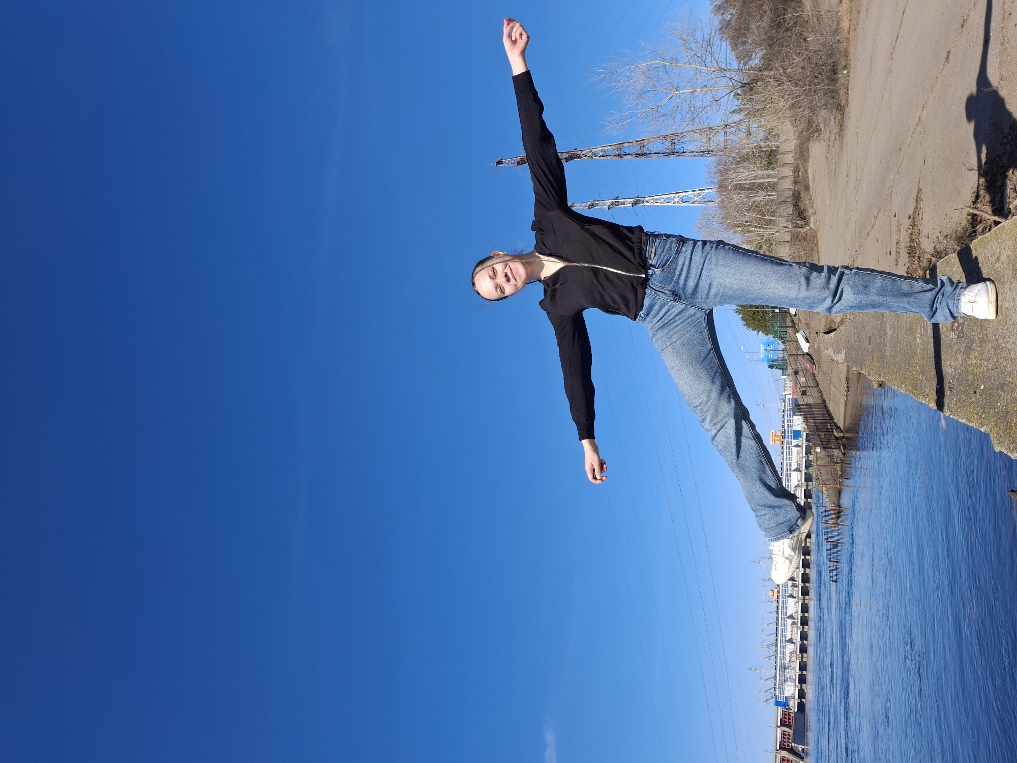 Woman photographs herself along Chaikovsky waterfront during sunny morning