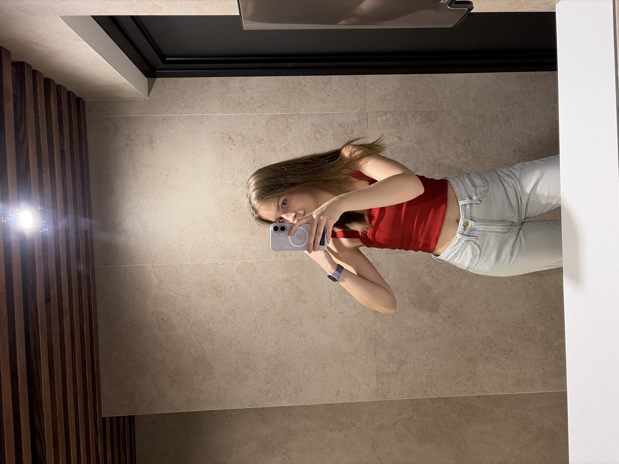 Mirror selfie in a Kyiv bathroom, red top and purple phone